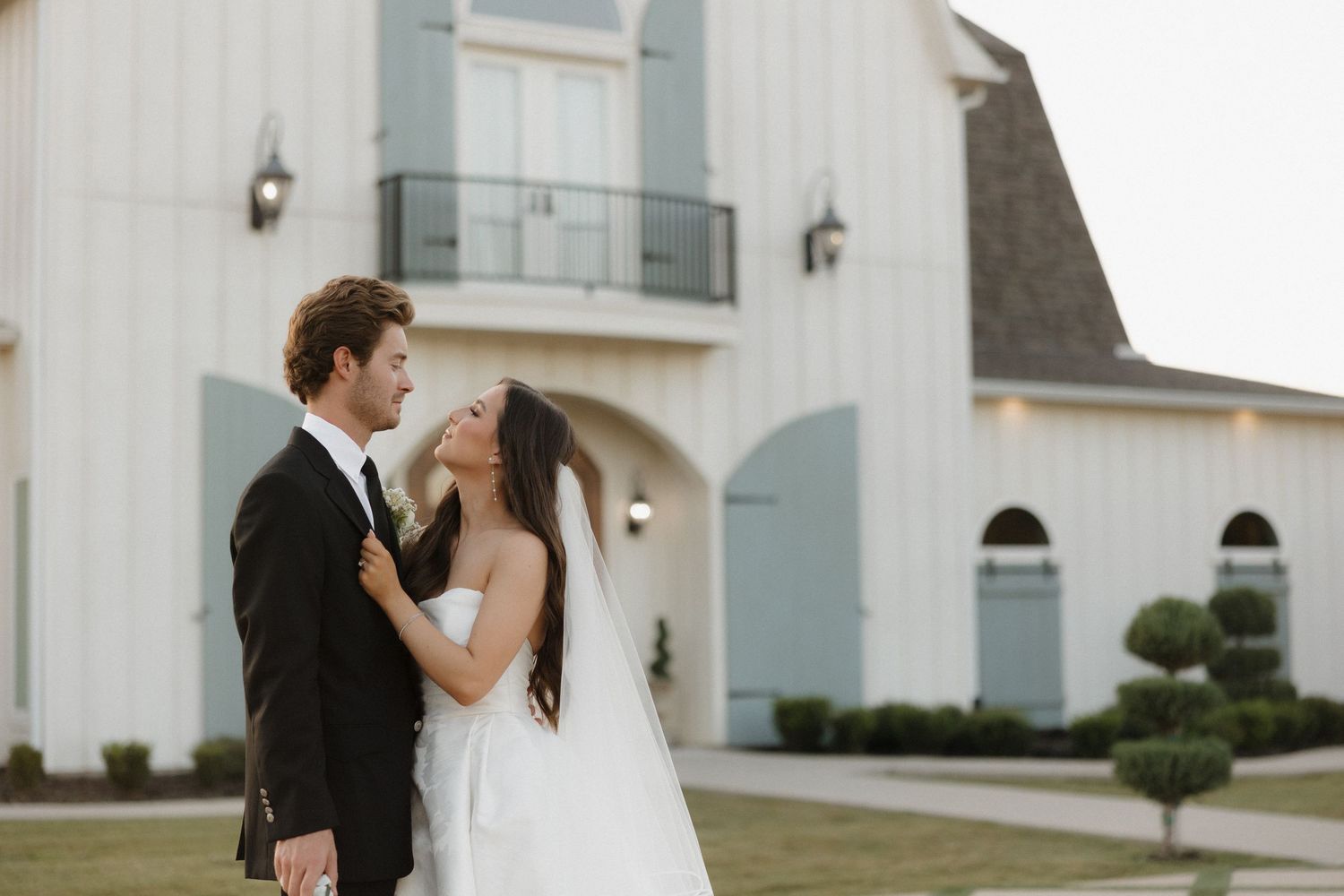 Bride and groom share romantic moments in front of a white church building during their wedding day celebration.