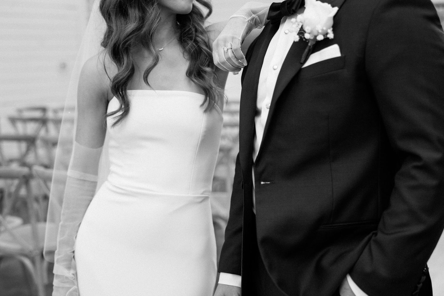 A bride and groom pose together in formal wedding attire for a black and white portrait.