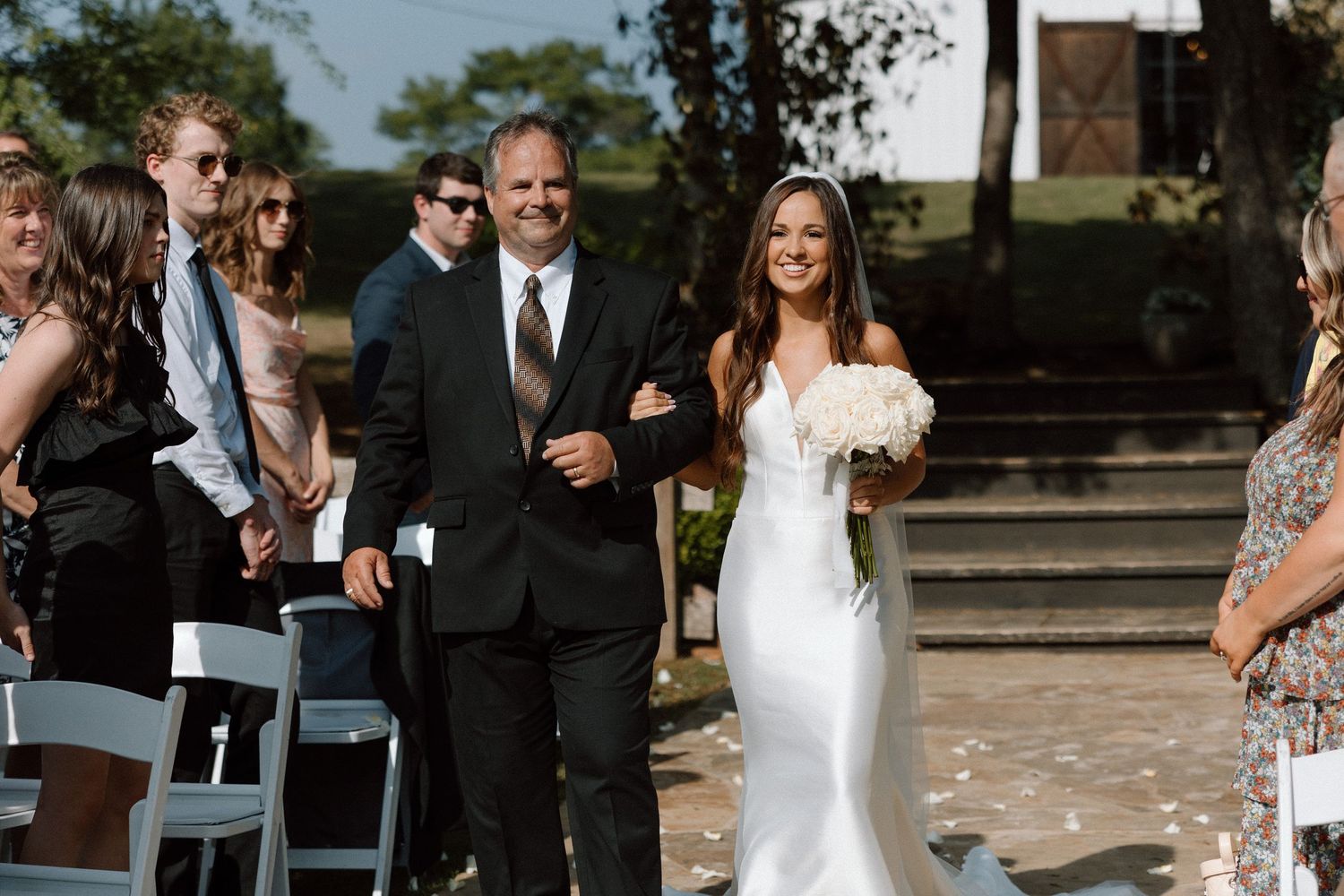Wedding guests shower happy newlyweds with confetti on outdoor steps during joyful celebration.
