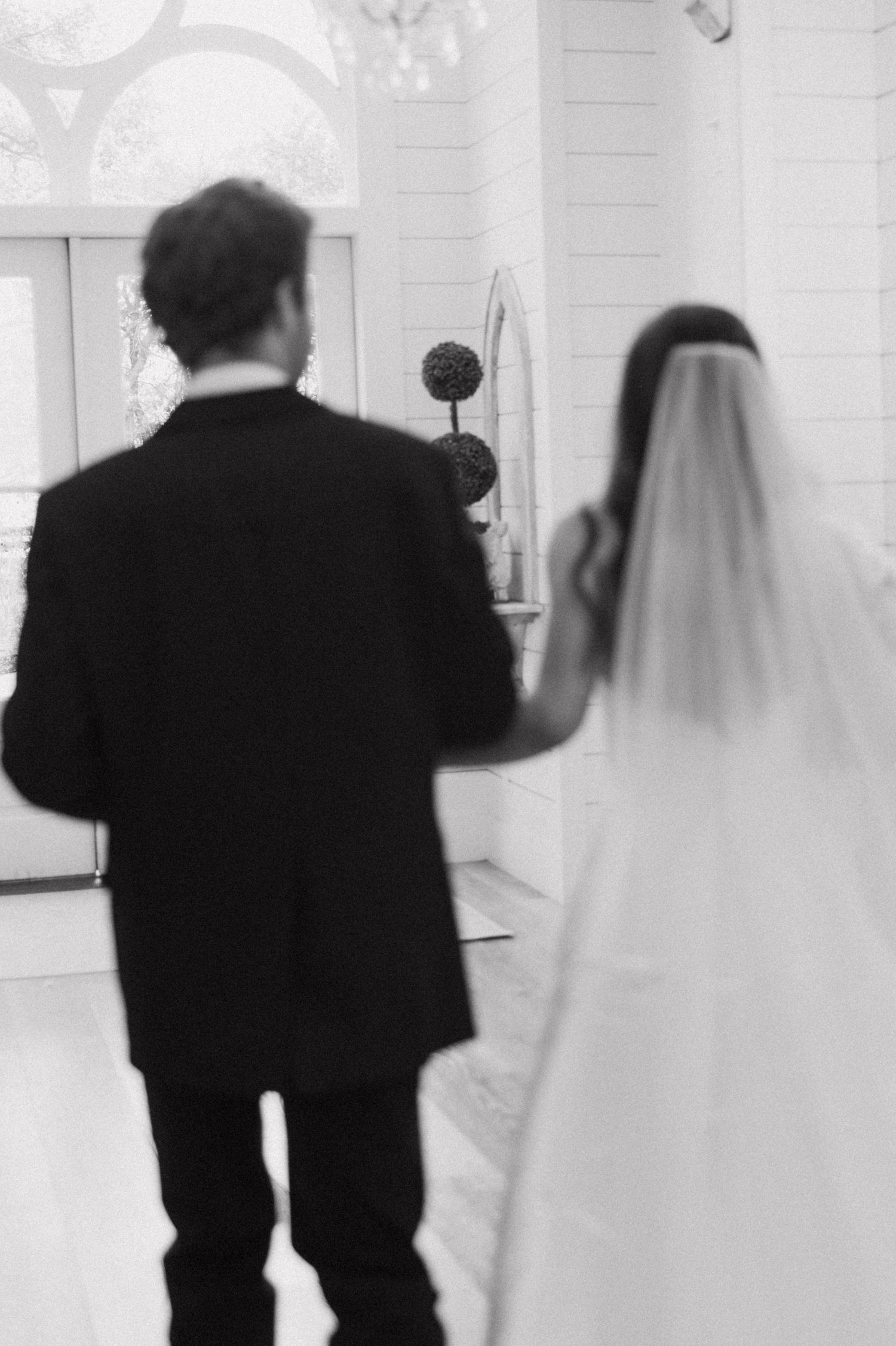 A sequence of black and white photos showing a couple walking together in wedding attire with the bride in a veil.