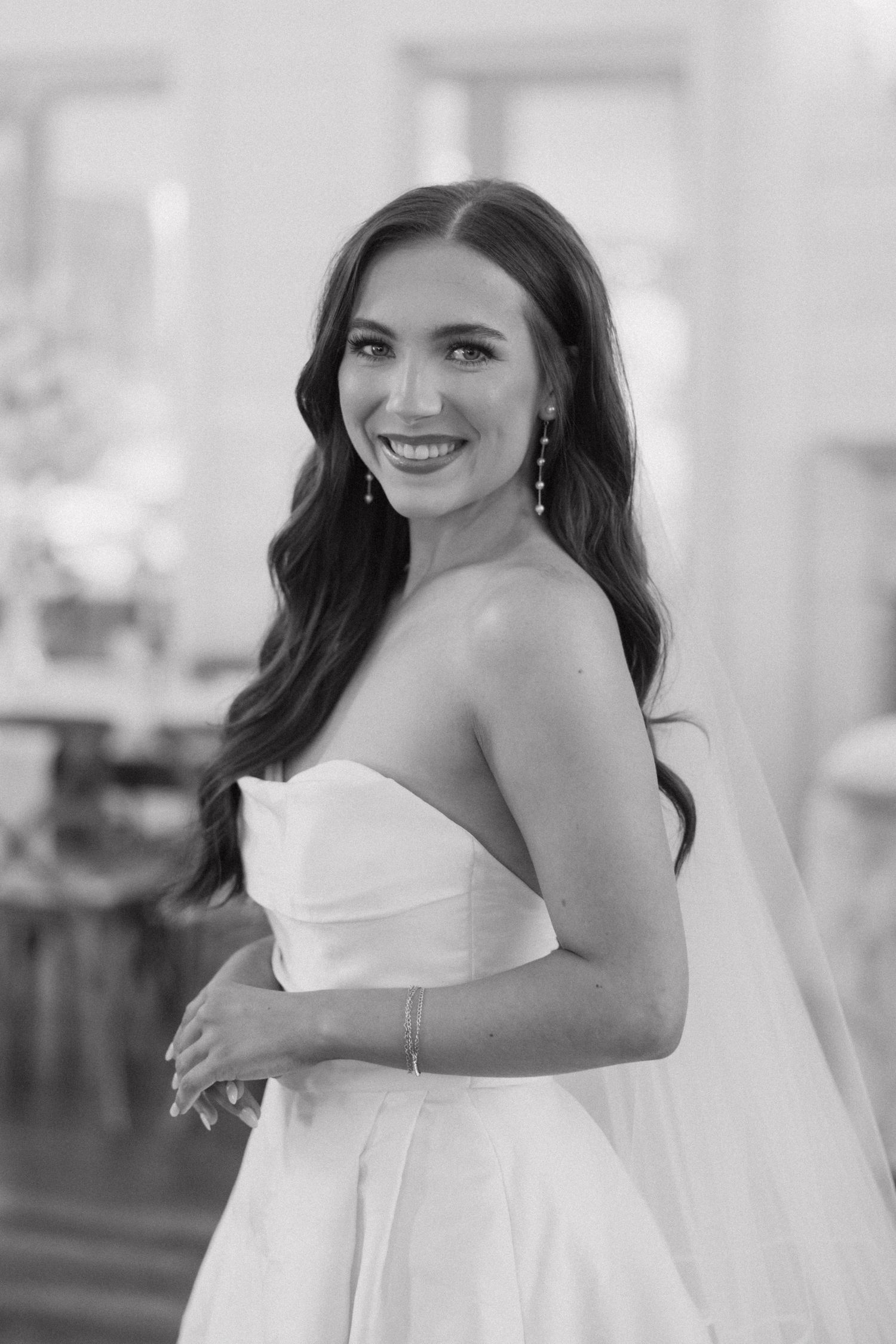 Black and white portrait series of a bride in a strapless wedding gown smiling and posing outdoors.
