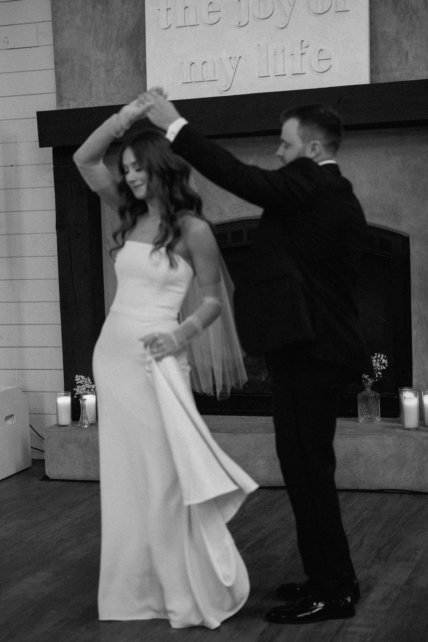 A couple performs a romantic dance sequence in black and white with text on the wall behind them.