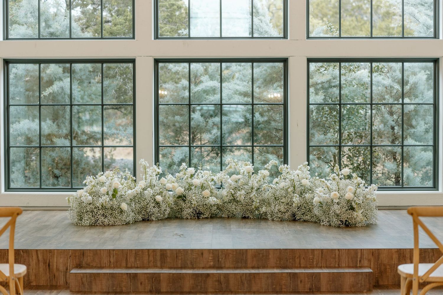 A modern wedding venue with floor-to-ceiling windows and white floral arrangements creating an elegant atmosphere.