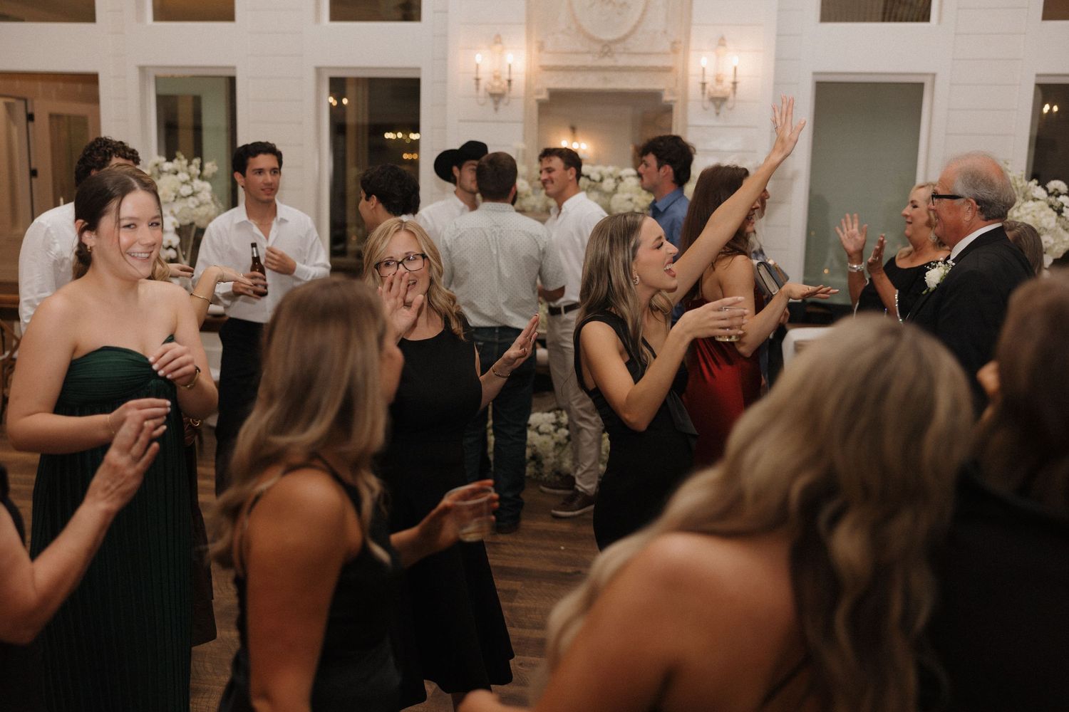 Wedding guests dance and celebrate on a crowded dance floor during an evening reception.
