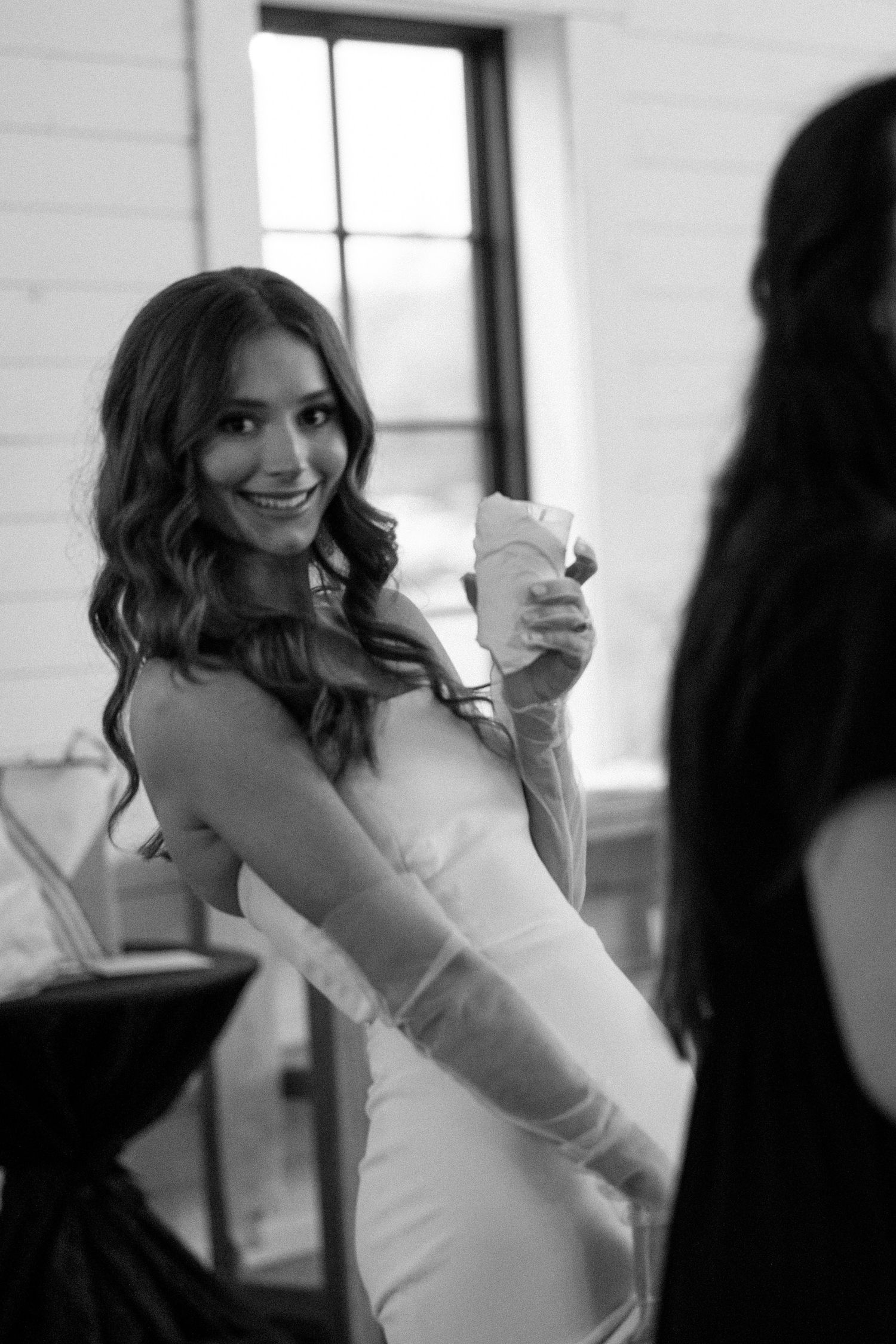 A series of four black and white photos showing a person in a white dress laughing and posing in an interior setting.