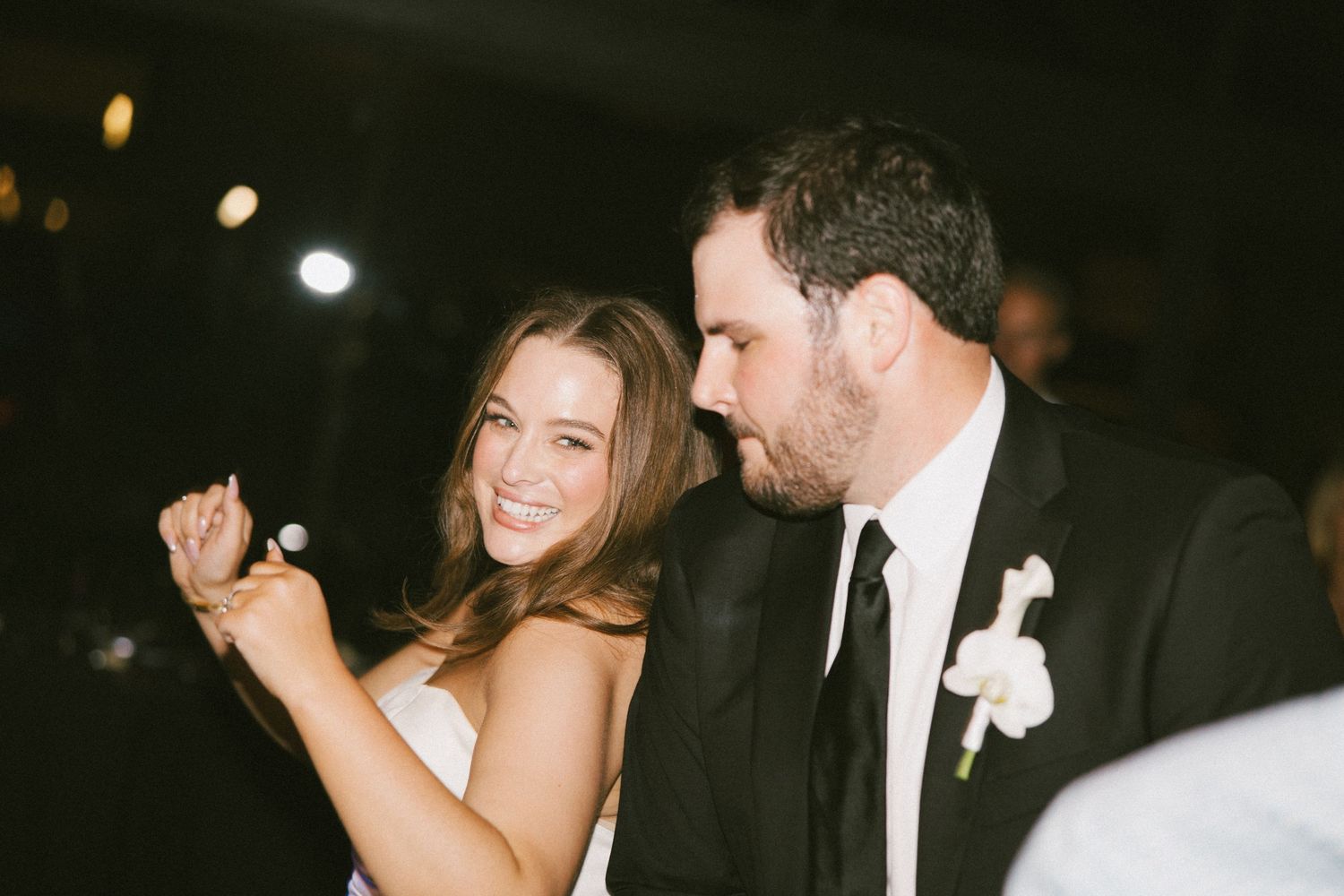 Bride and groom sharing a joyful moment at their wedding reception, groom wearing boutonniere.