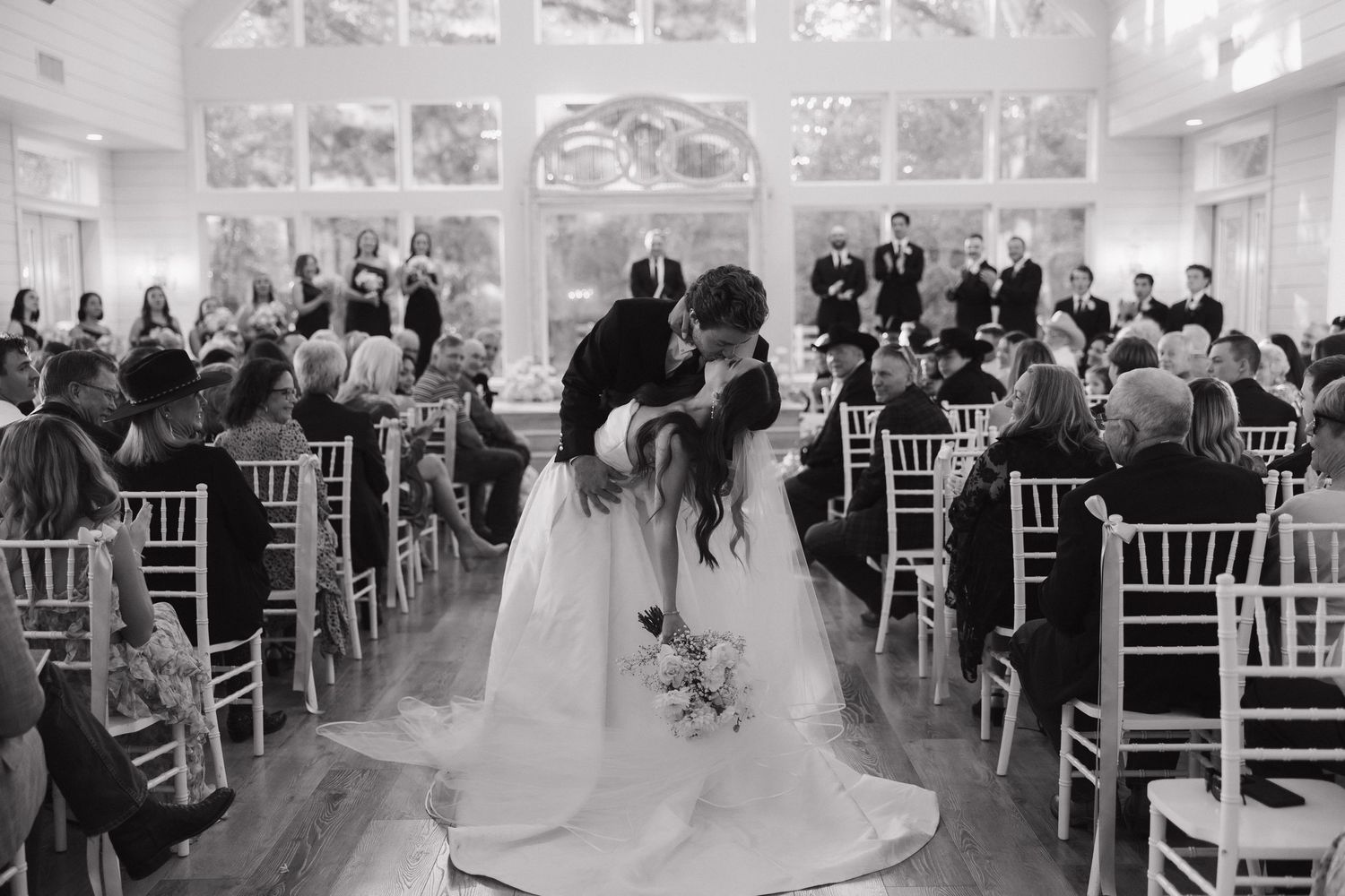 A wedding ceremony montage showing multiple angles of a white-decorated indoor venue with guests seated in white chairs.