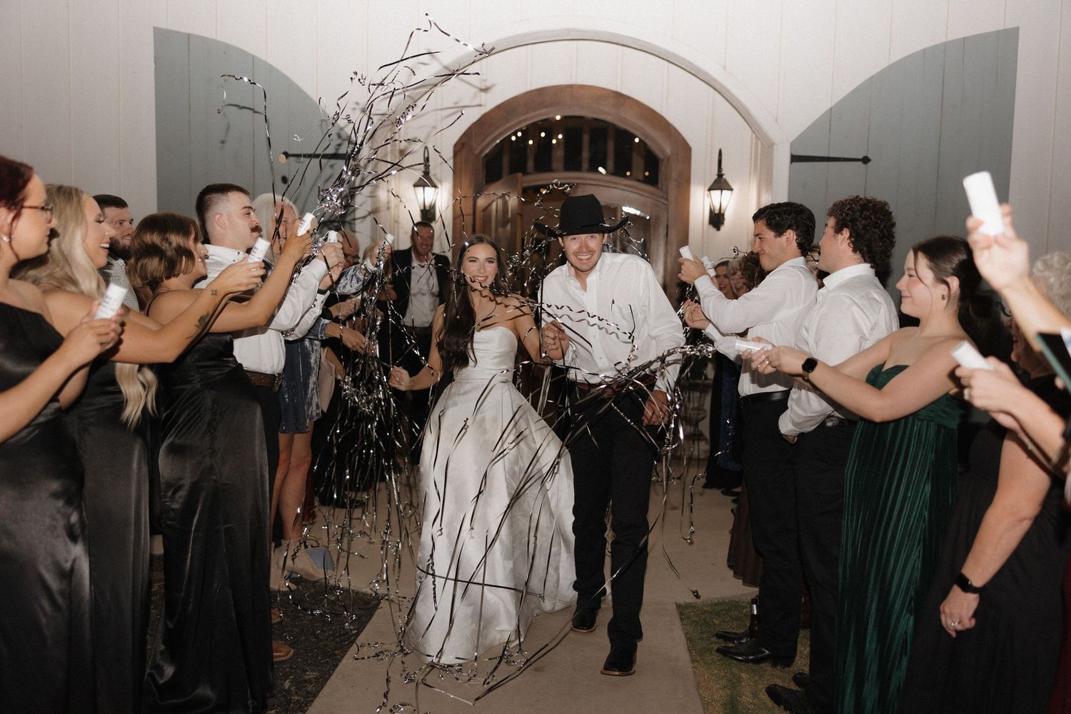 Wedding guests dance and celebrate on a dimly lit dance floor during an evening reception celebration.