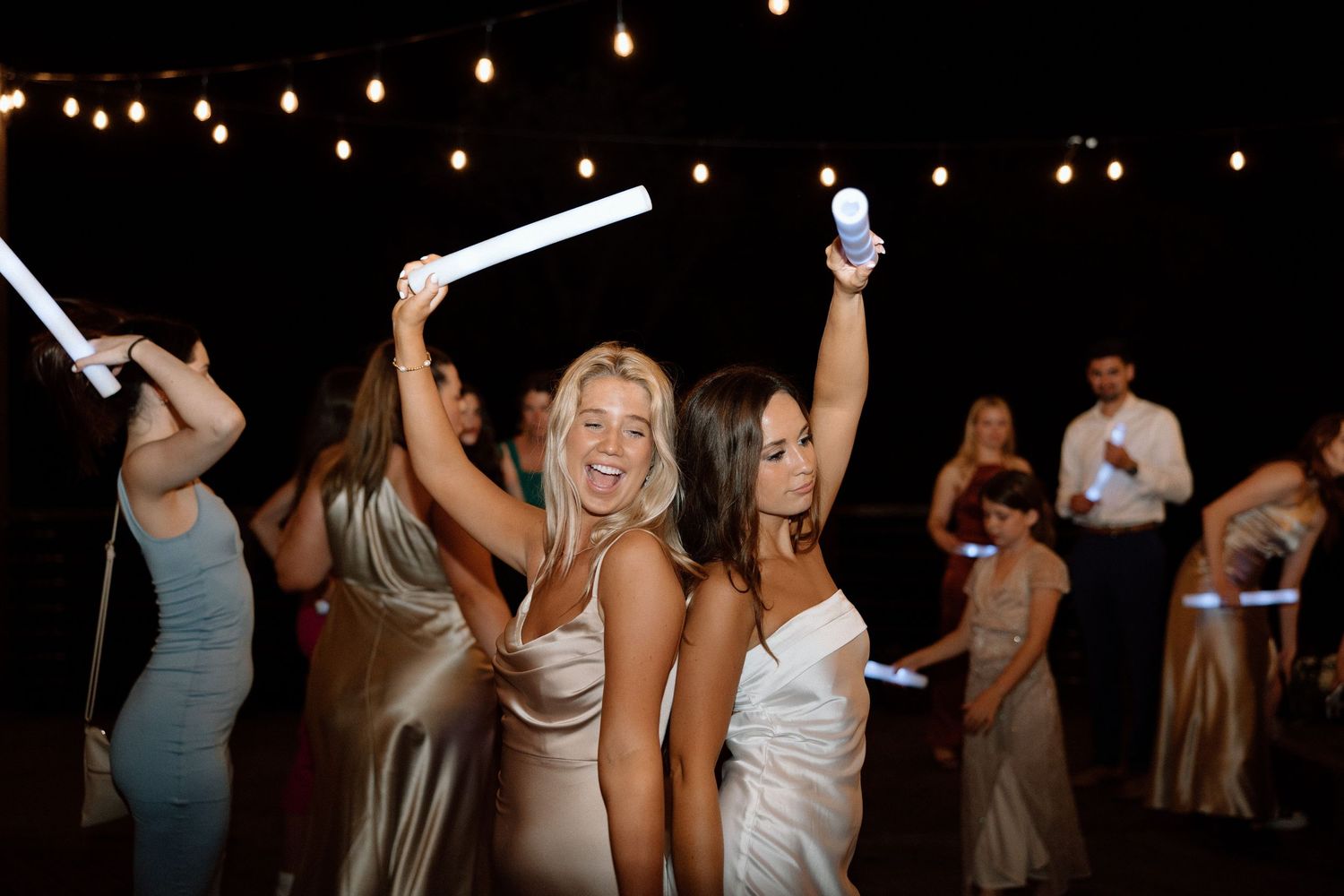 A group of people dancing and celebrating at a dimly lit party or nightclub event.
