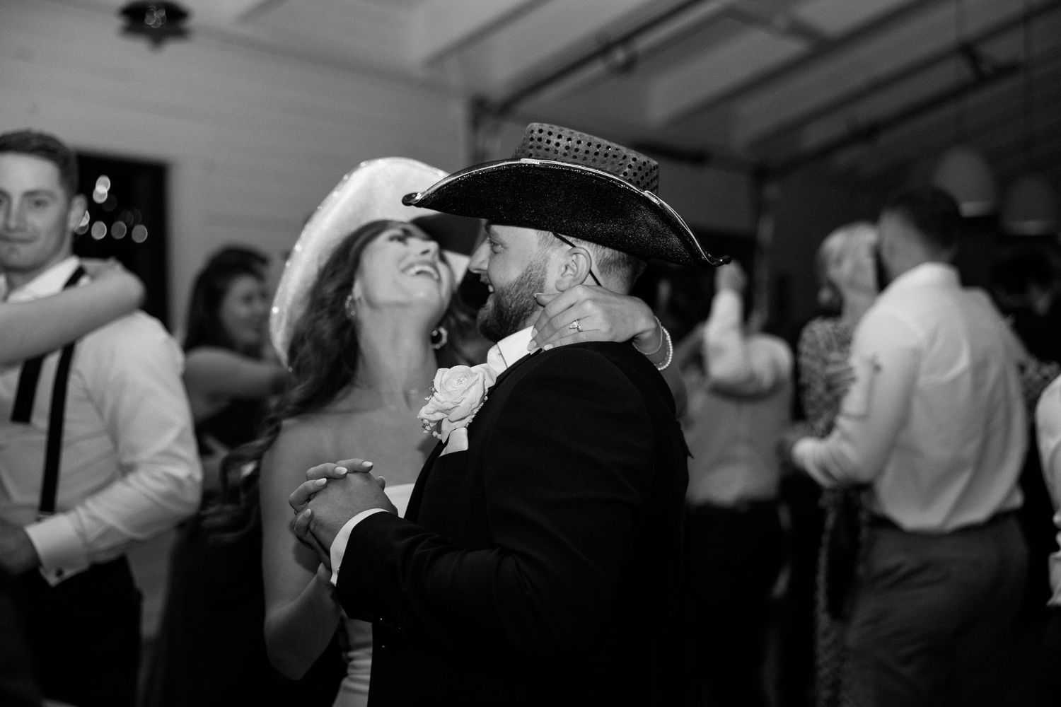 A couple dancing intimately at a party, captured in black and white photography.