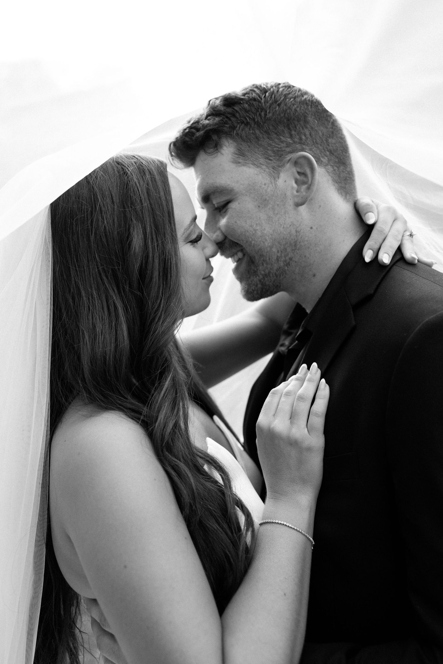 A romantic black and white photo series showing a couple in intimate poses behind sheer curtains.