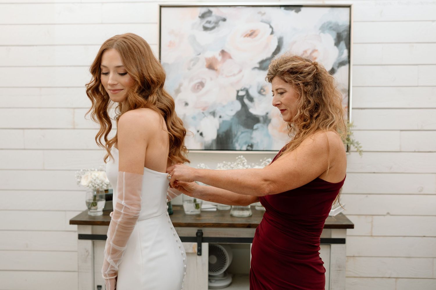 A bride in a white dress gets help with final adjustments to her gown before the wedding ceremony.