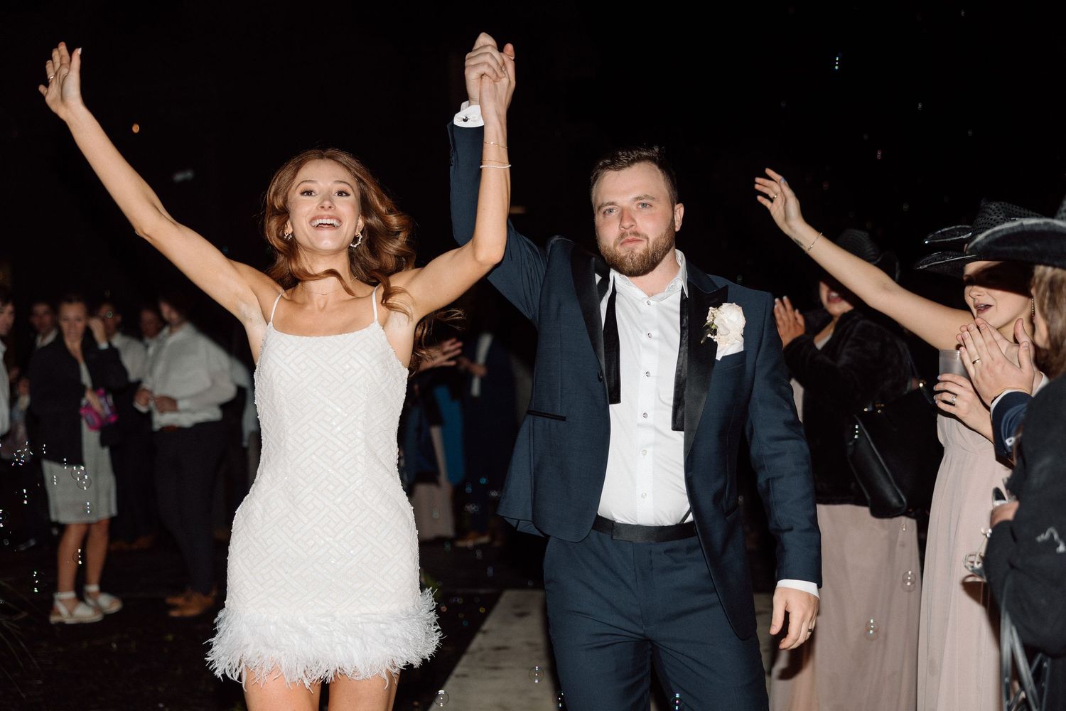 A couple performs their first dance at a wedding reception with guests watching in the background.