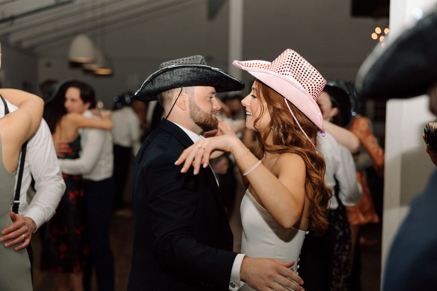 A group of wedding guests dancing and celebrating together on a dance floor at a reception party.