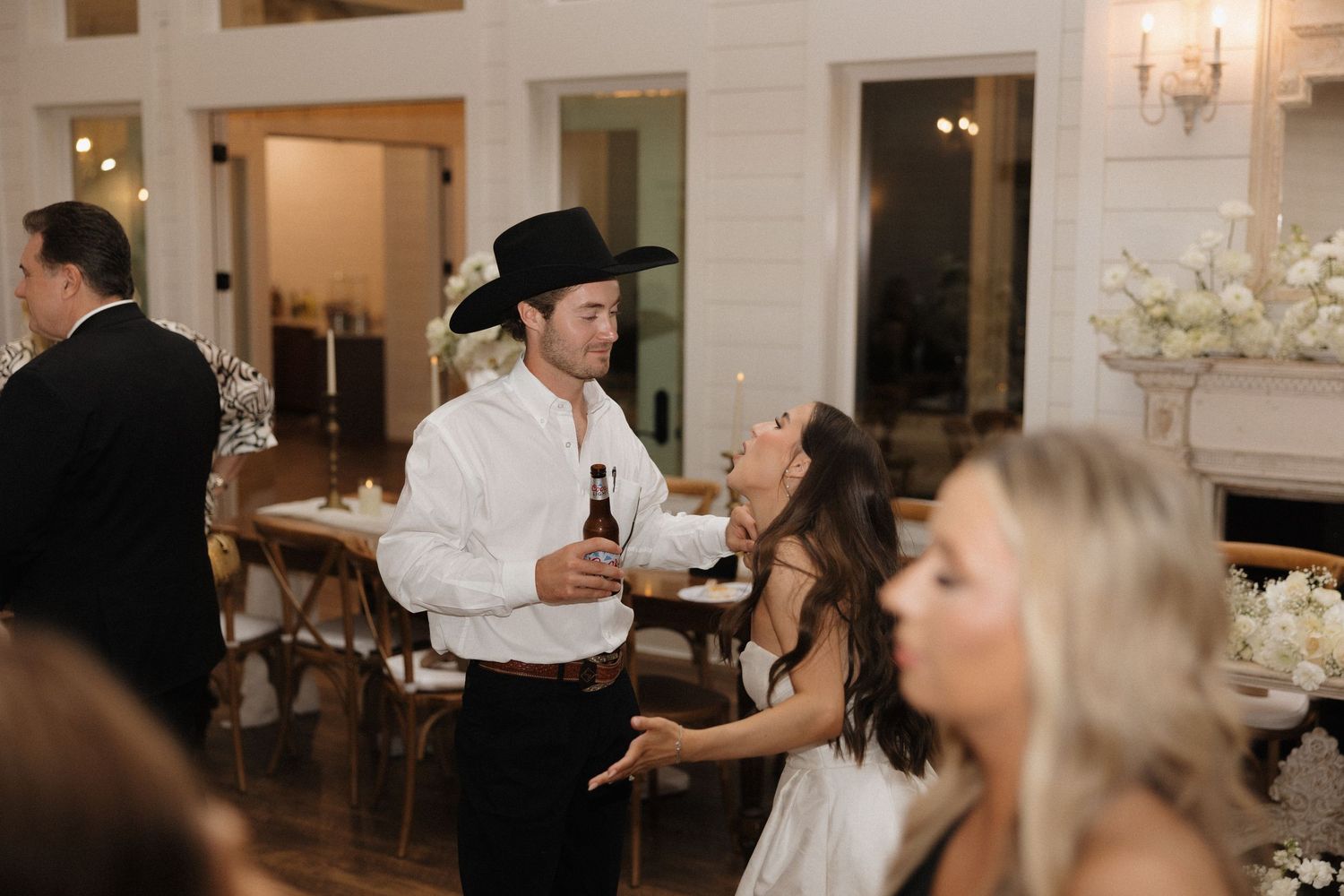 Wedding guests dance and celebrate at an elegant indoor reception with warm lighting and festive atmosphere.