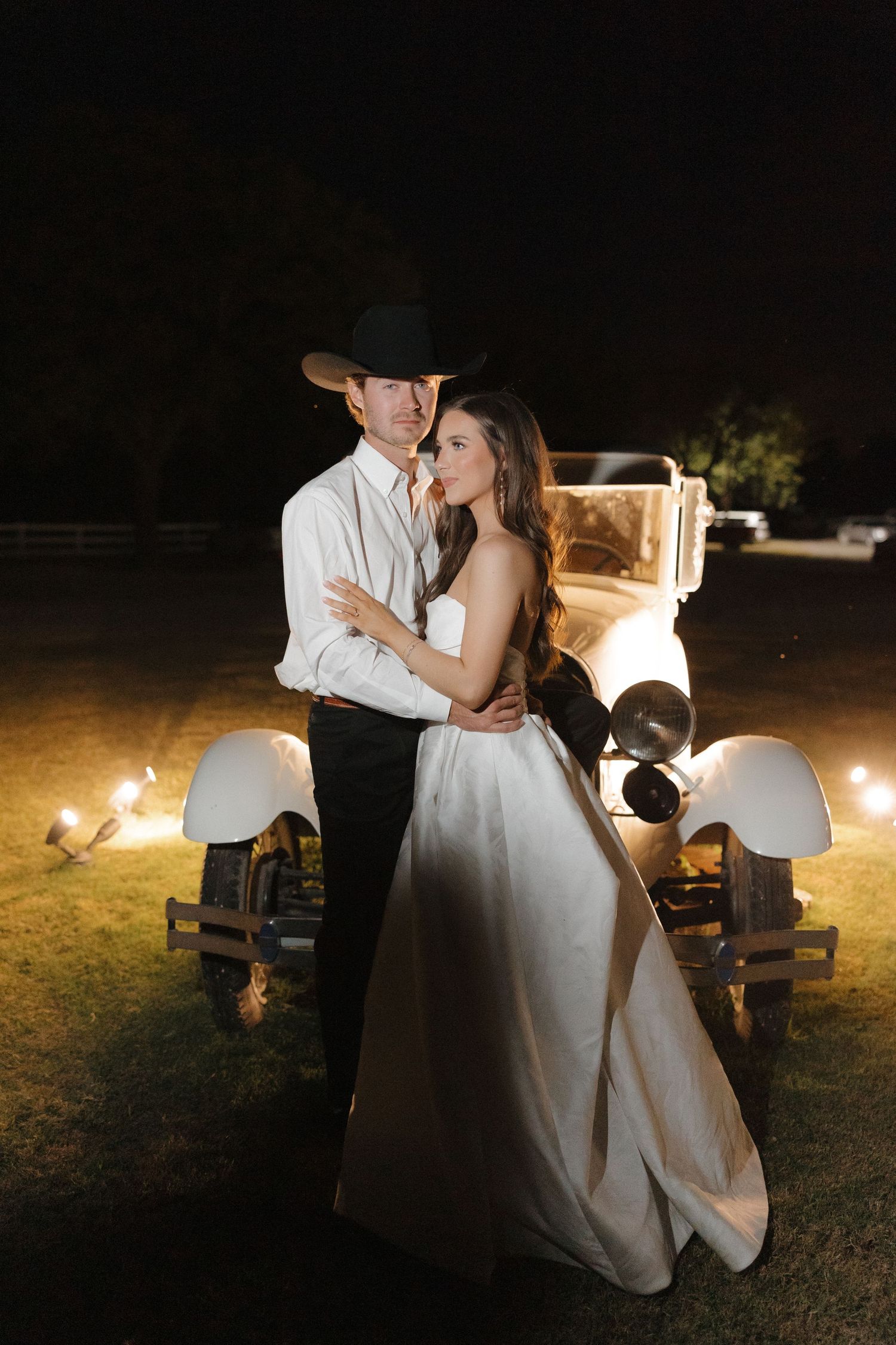 A romantic nighttime dance scene between a couple in formal attire illuminated by soft outdoor lighting.