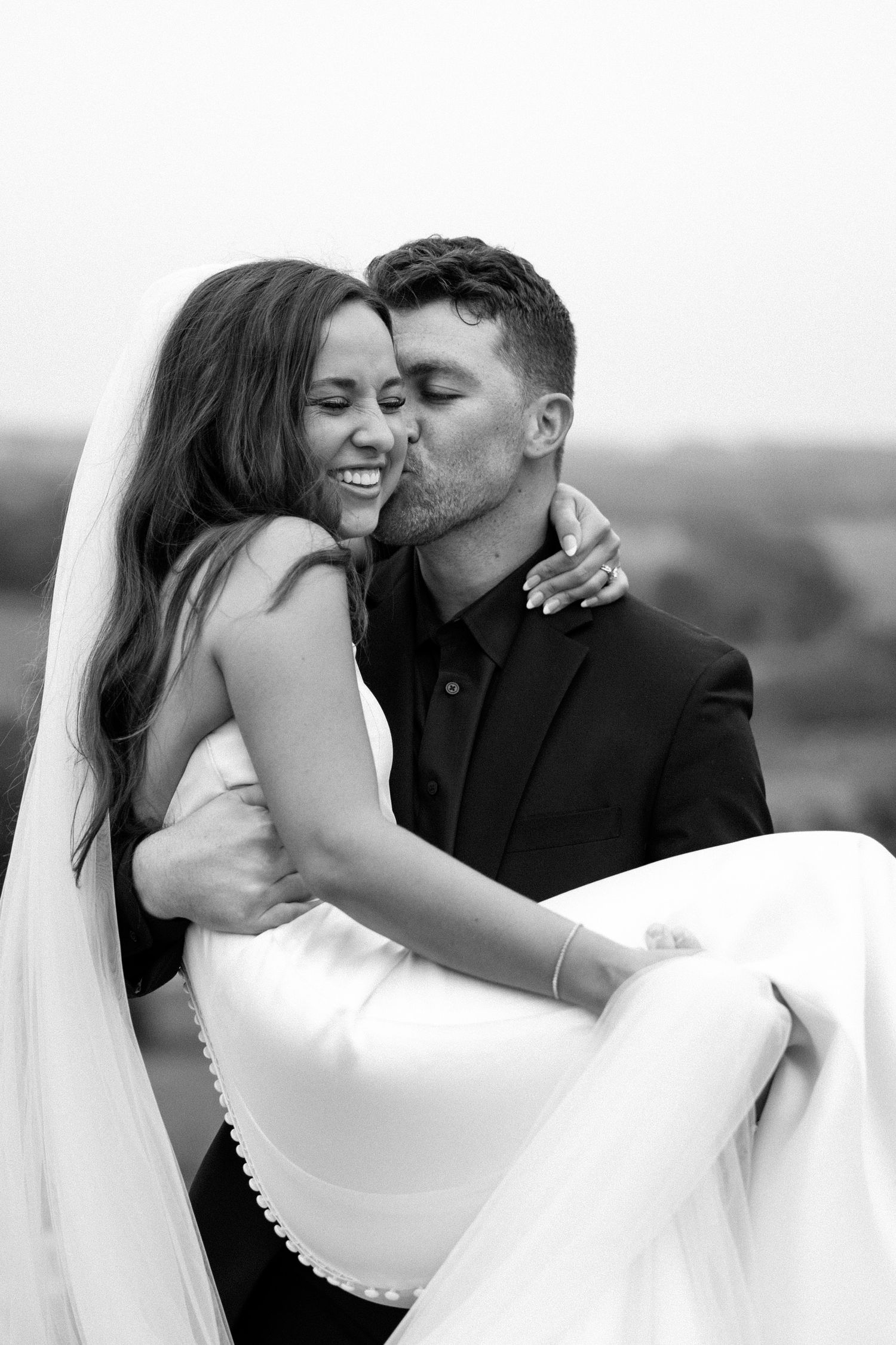 A series of romantic black and white wedding photos showing tender kisses between a couple in formal attire.