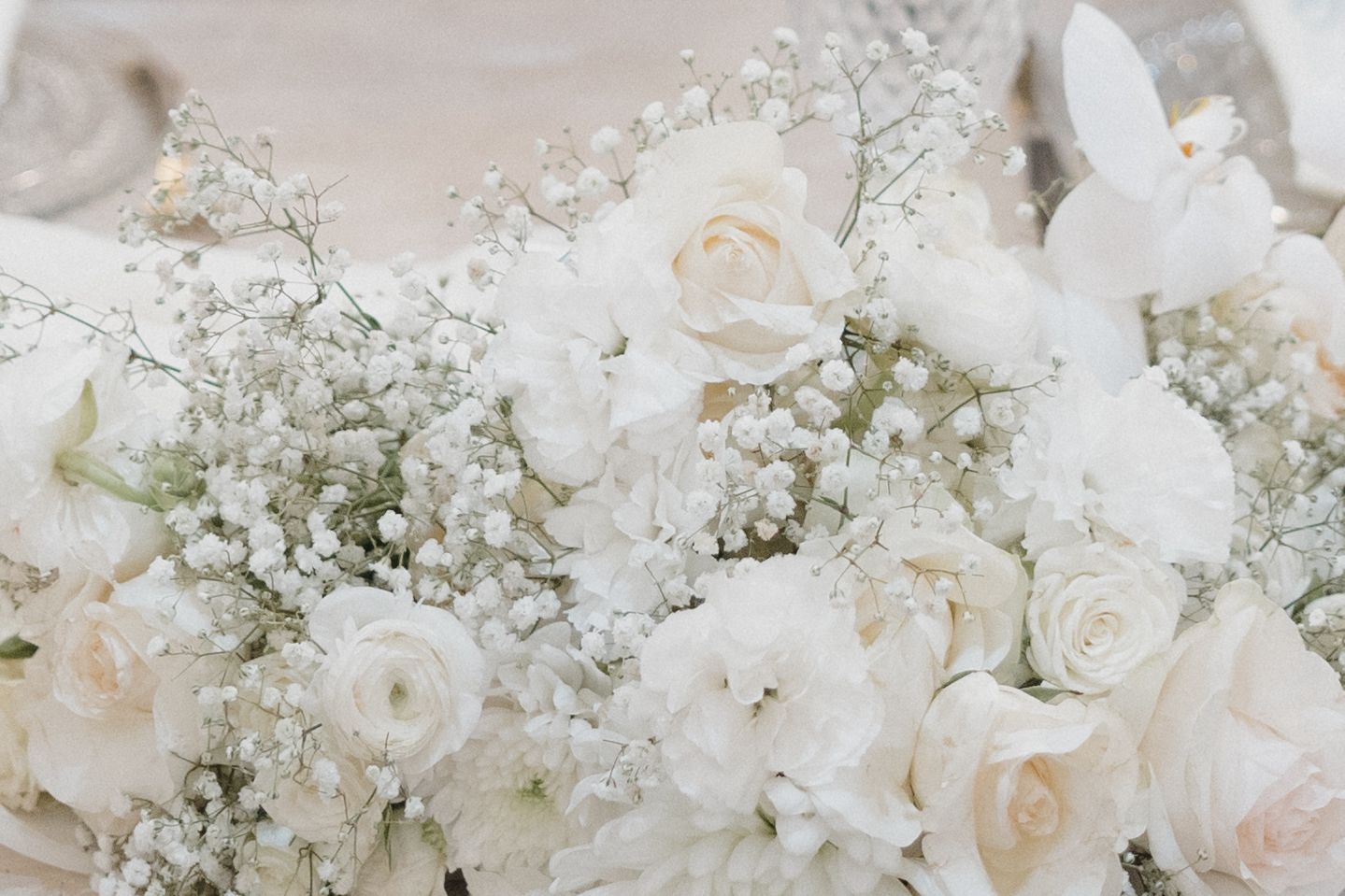 Delicate arrangement of white roses and baby's breath flowers creating an ethereal wedding bouquet display.