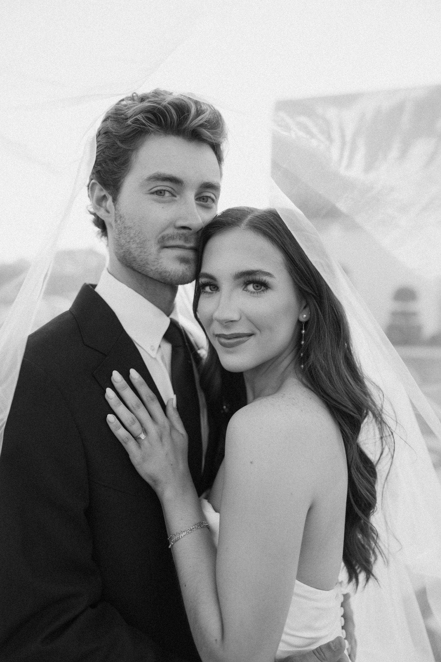 A romantic black and white photo series showing a couple in formal attire embracing under a veil.