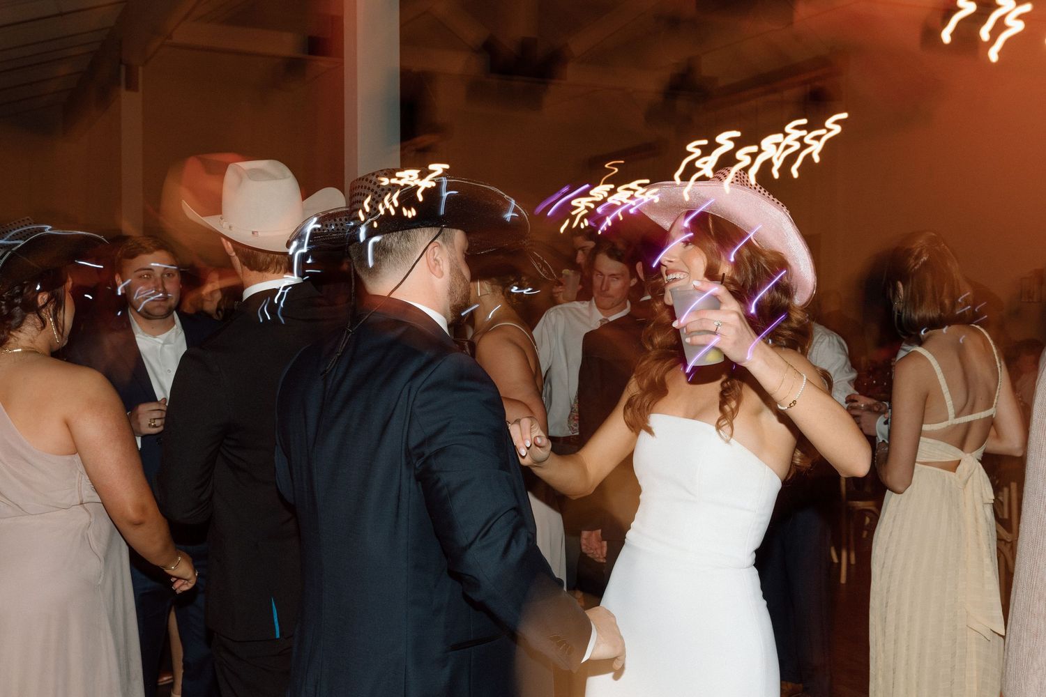 Wedding guests dancing together on the dance floor during a reception celebration.