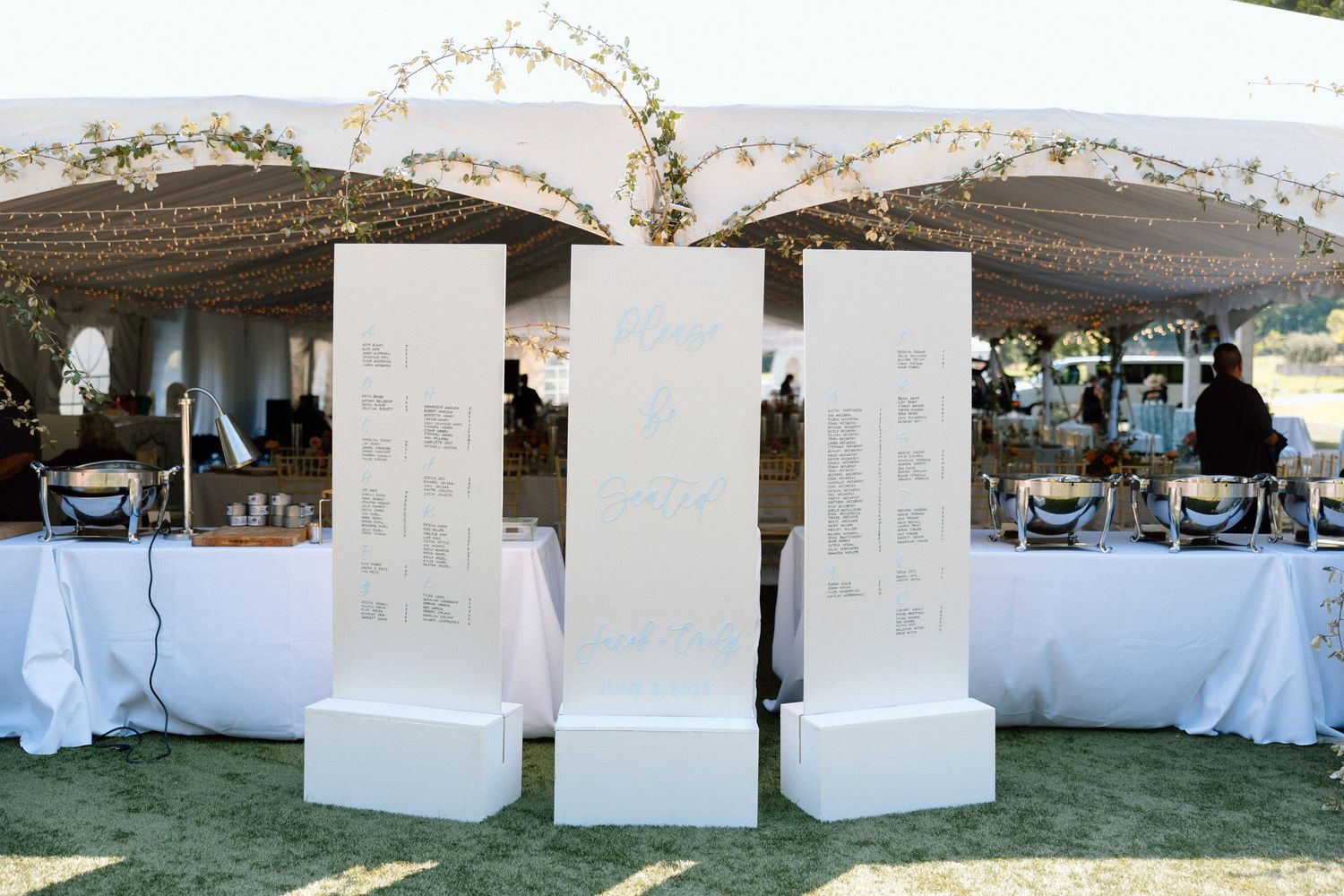 White fabric panels create an elegant outdoor wedding seating arrangement with string lights overhead at dusk.