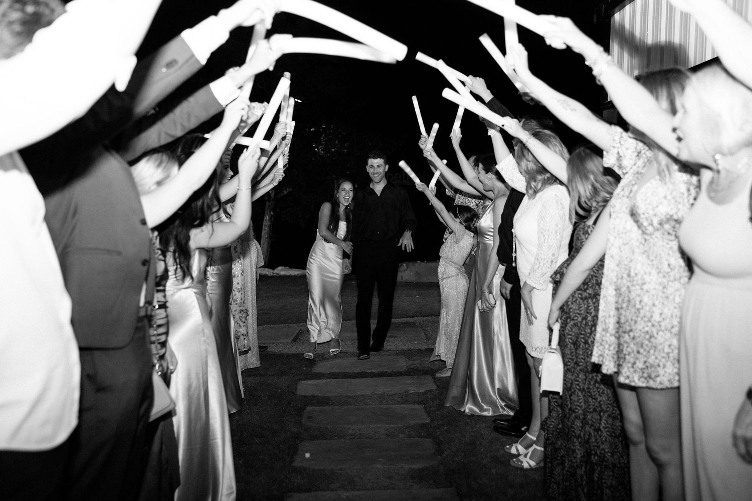 A black and white photo shows a crowd of people dancing together in formal attire at an elegant ballroom event.