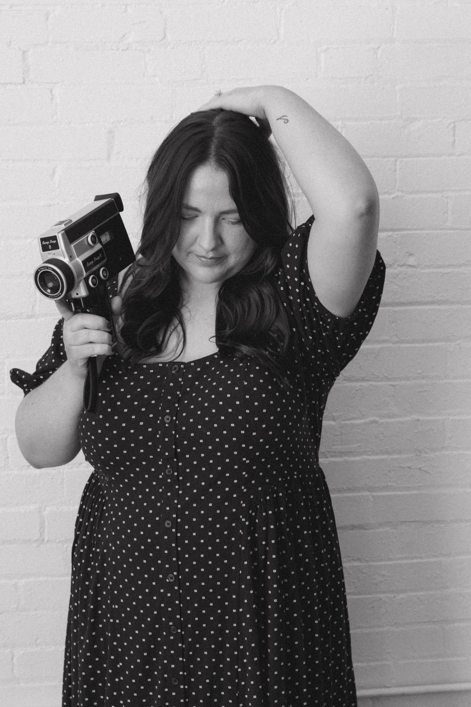 A series of black and white photos showing someone in a polka dot dress holding a vintage camera against a white wall.