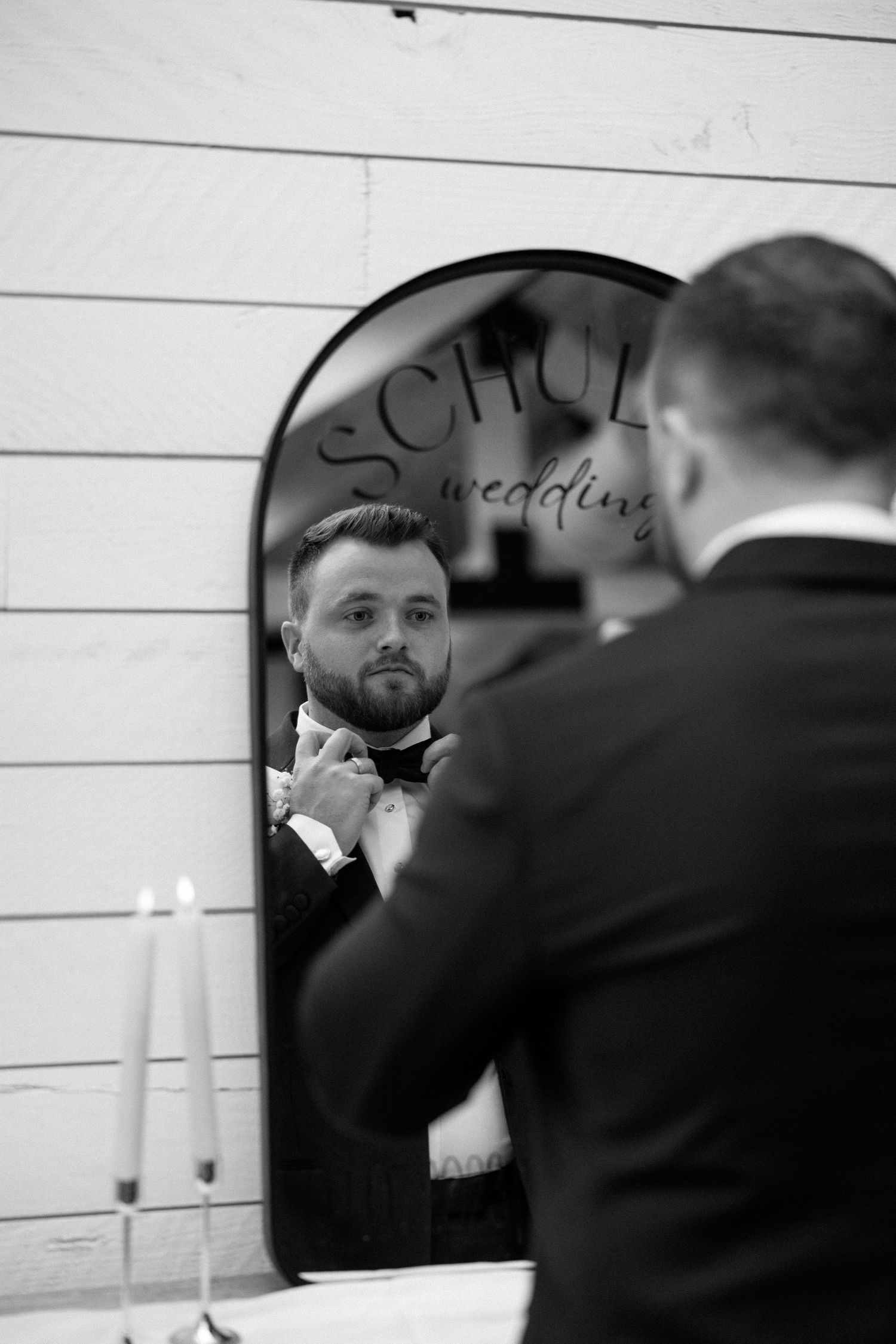 A black and white series of mirror reflections shows someone adjusting their tie before an event.