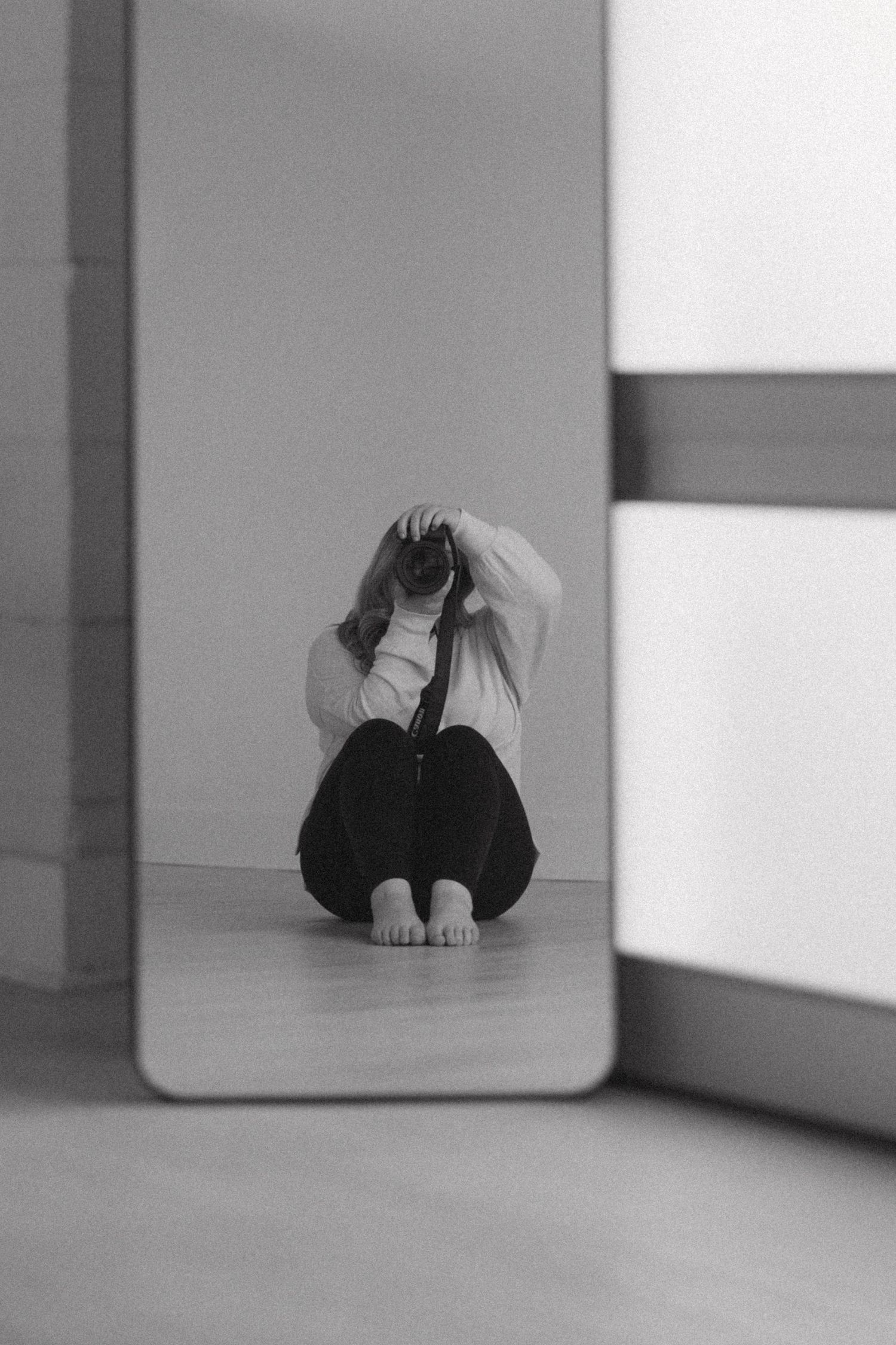 Minimalist black and white composition showing geometric shapes and shadows on a light surface.