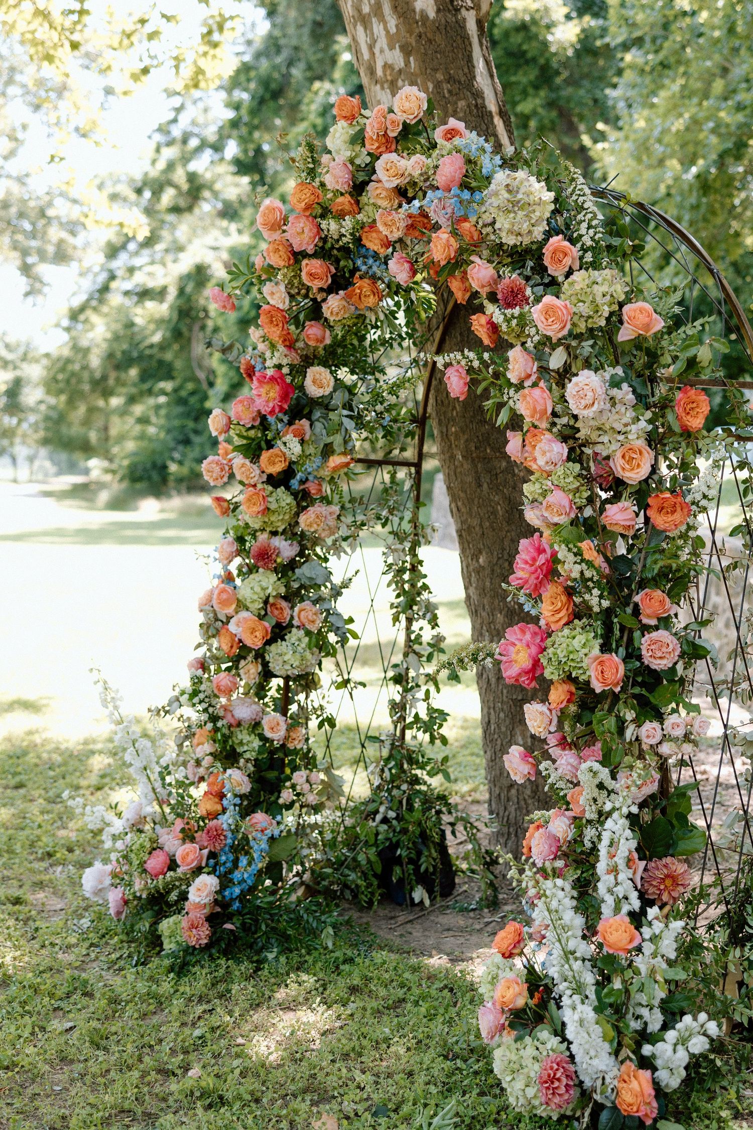 A romantic floral arch adorned with peach and pink roses creates an enchanting garden wedding backdrop.