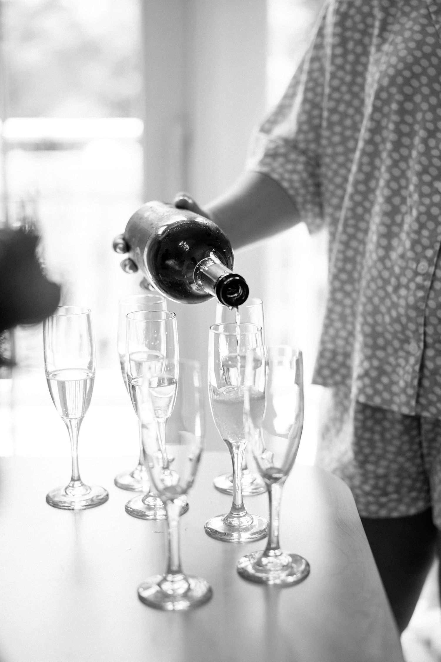 Champagne being poured into elegant flute glasses at an event in black and white photography.