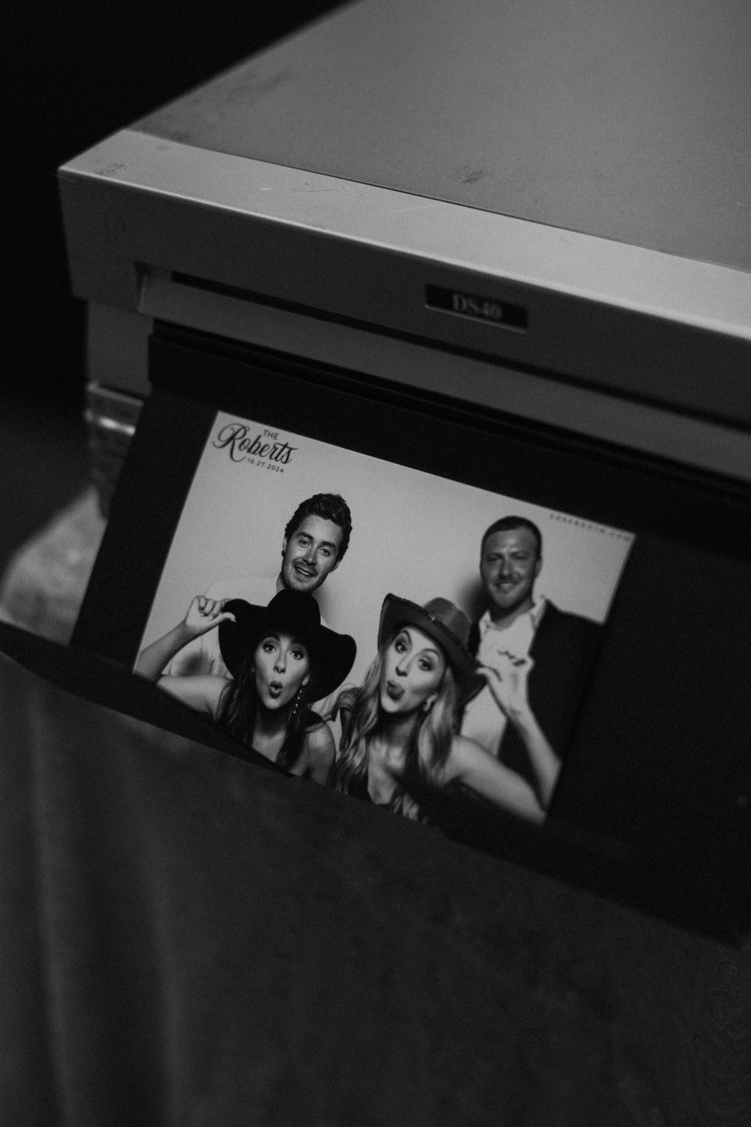 A black and white photo of a group portrait print emerging from a printer in low light.