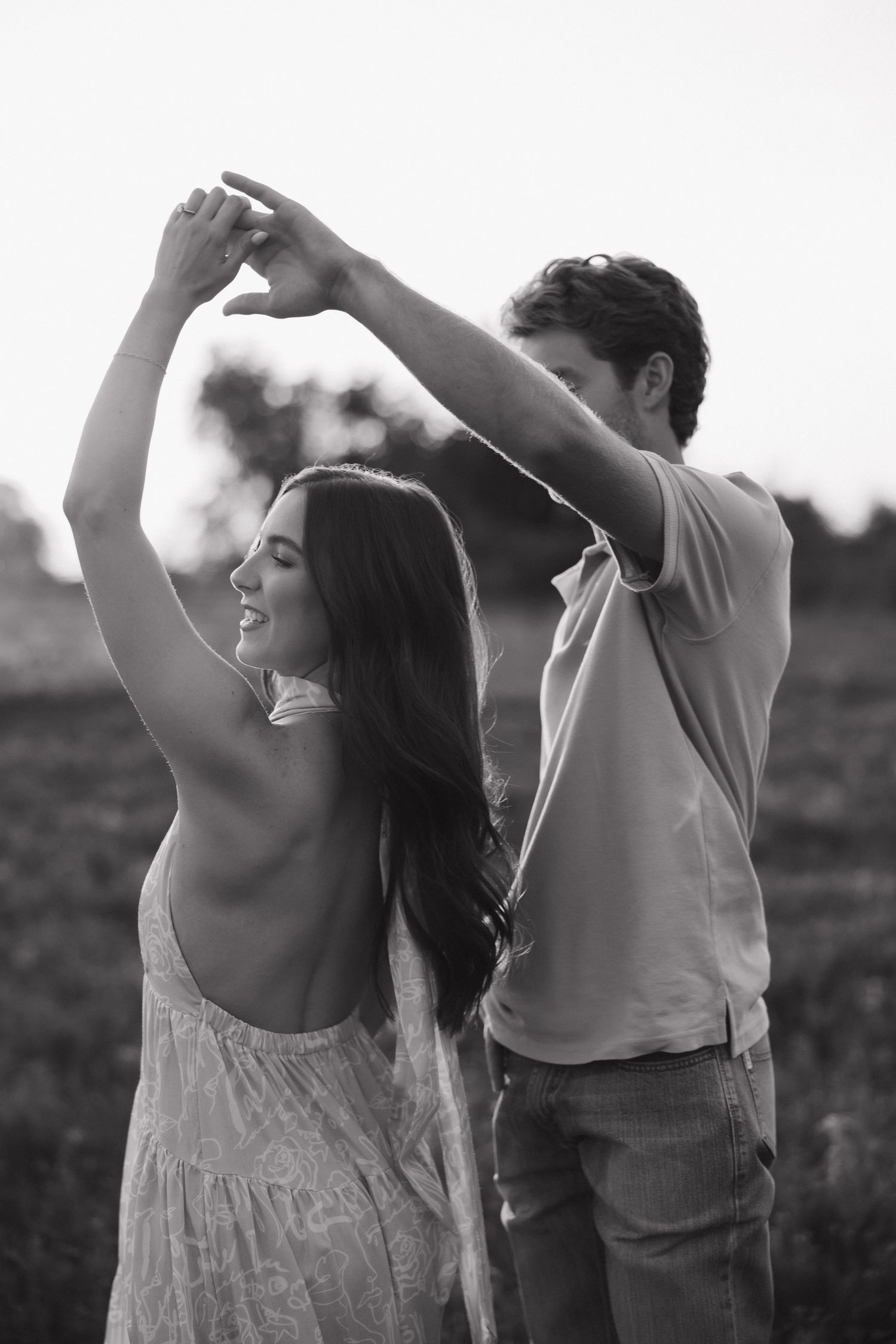 A romantic black and white photo of a couple dancing together in a field.