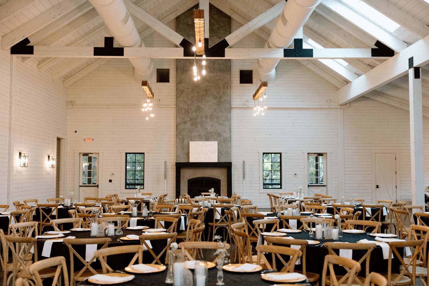 A bright, modern restaurant interior with white walls, wooden tables and chairs, and pendant lighting creating an airy atmosphere.