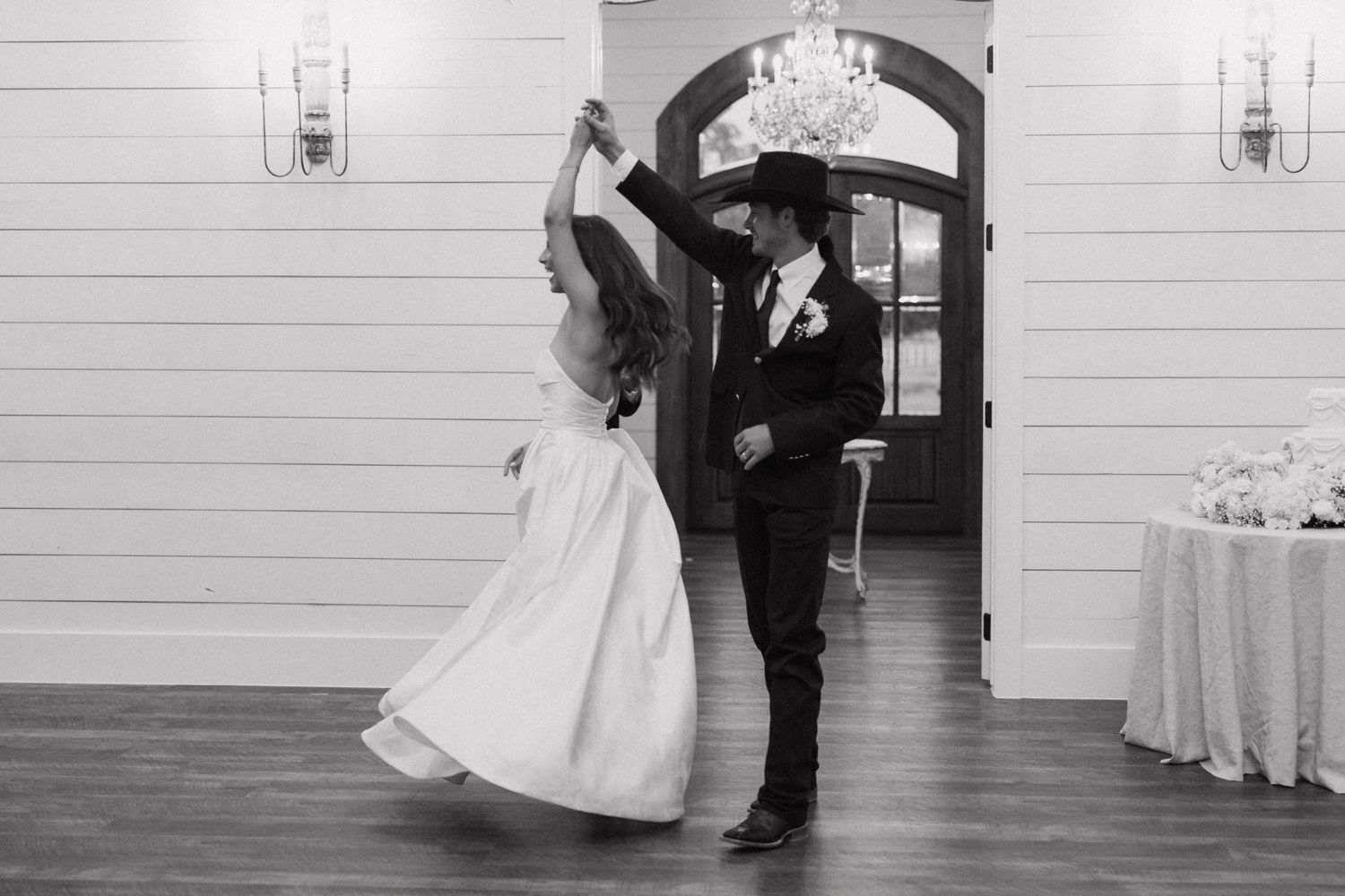 A couple dancing together at their wedding reception in a rustic venue with white shiplap walls.