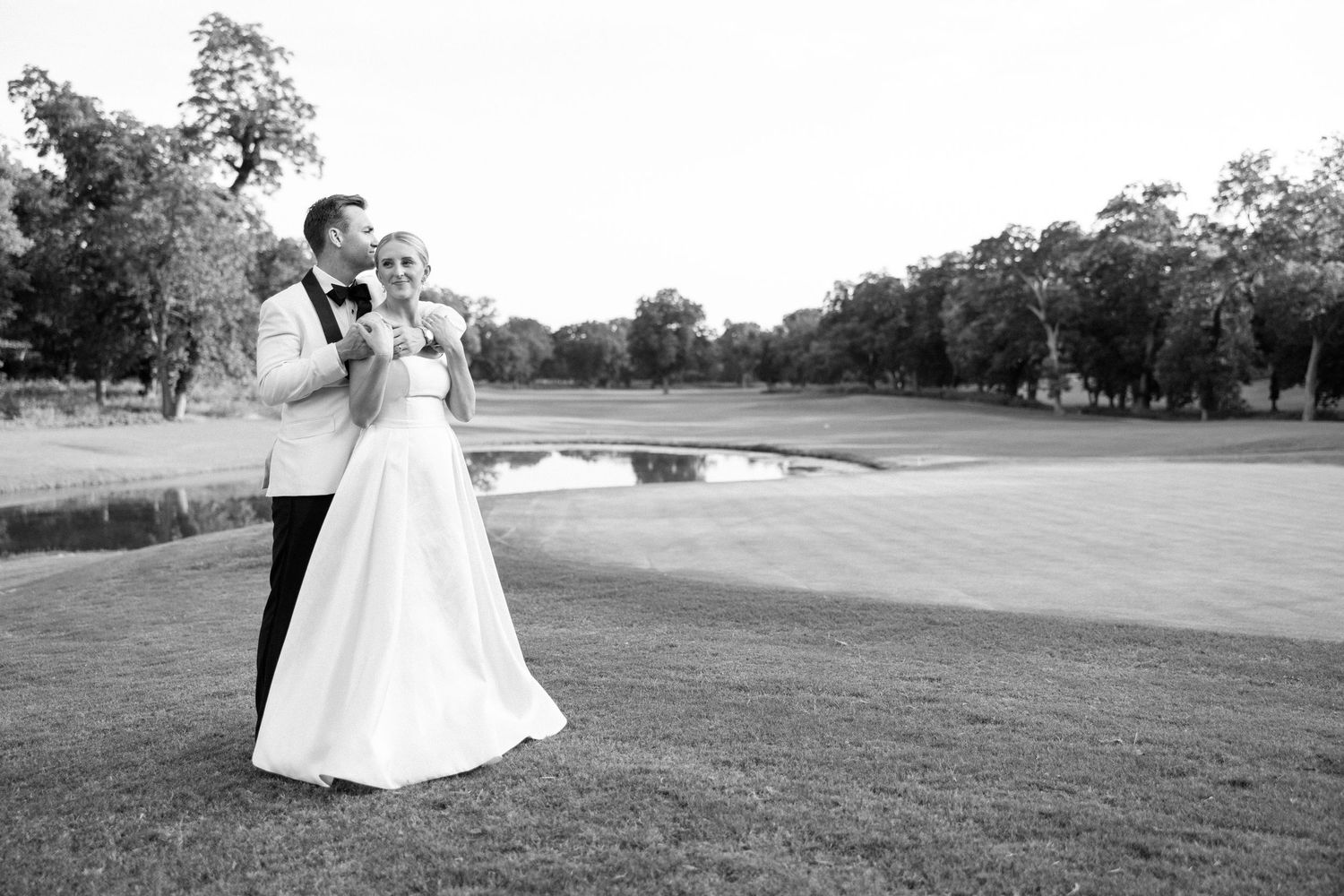 A bride in a flowing white wedding dress twirls gracefully on a scenic golf course during a wedding photoshoot.