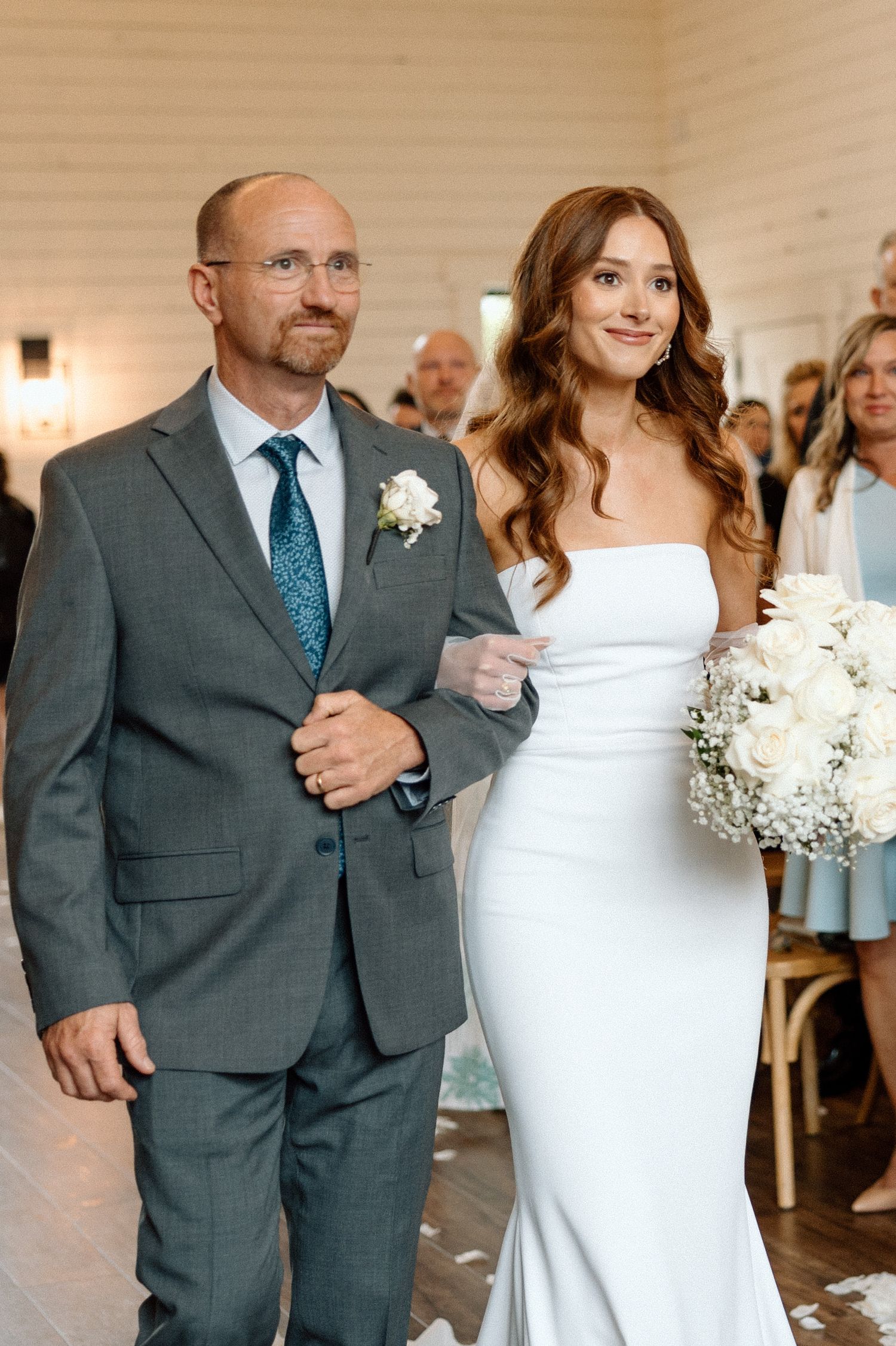 A wedding scene showing a couple walking down a hallway in formal attire with white floral decorations.