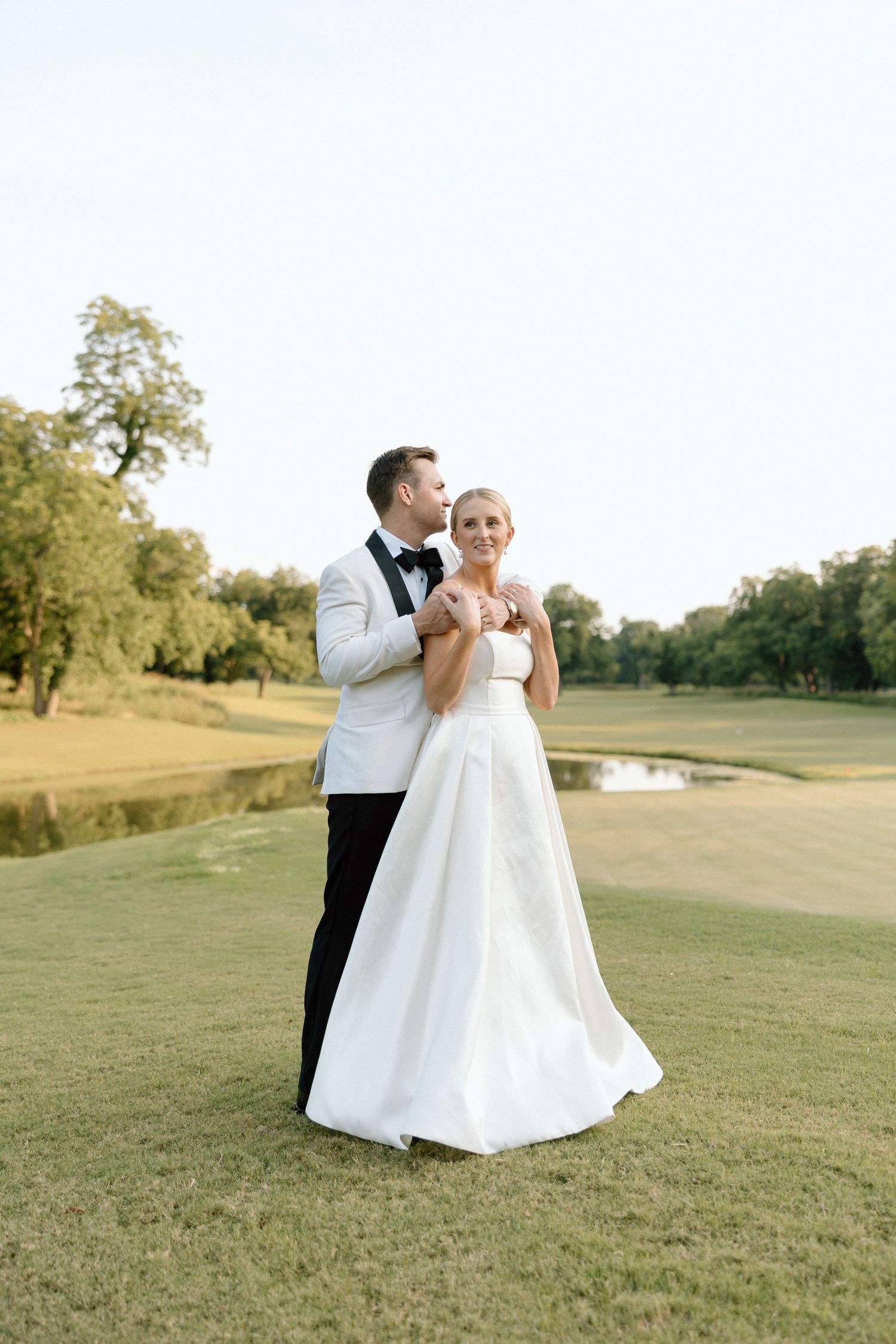 A couple in wedding attire dances together on a lush green golf course during their special day.