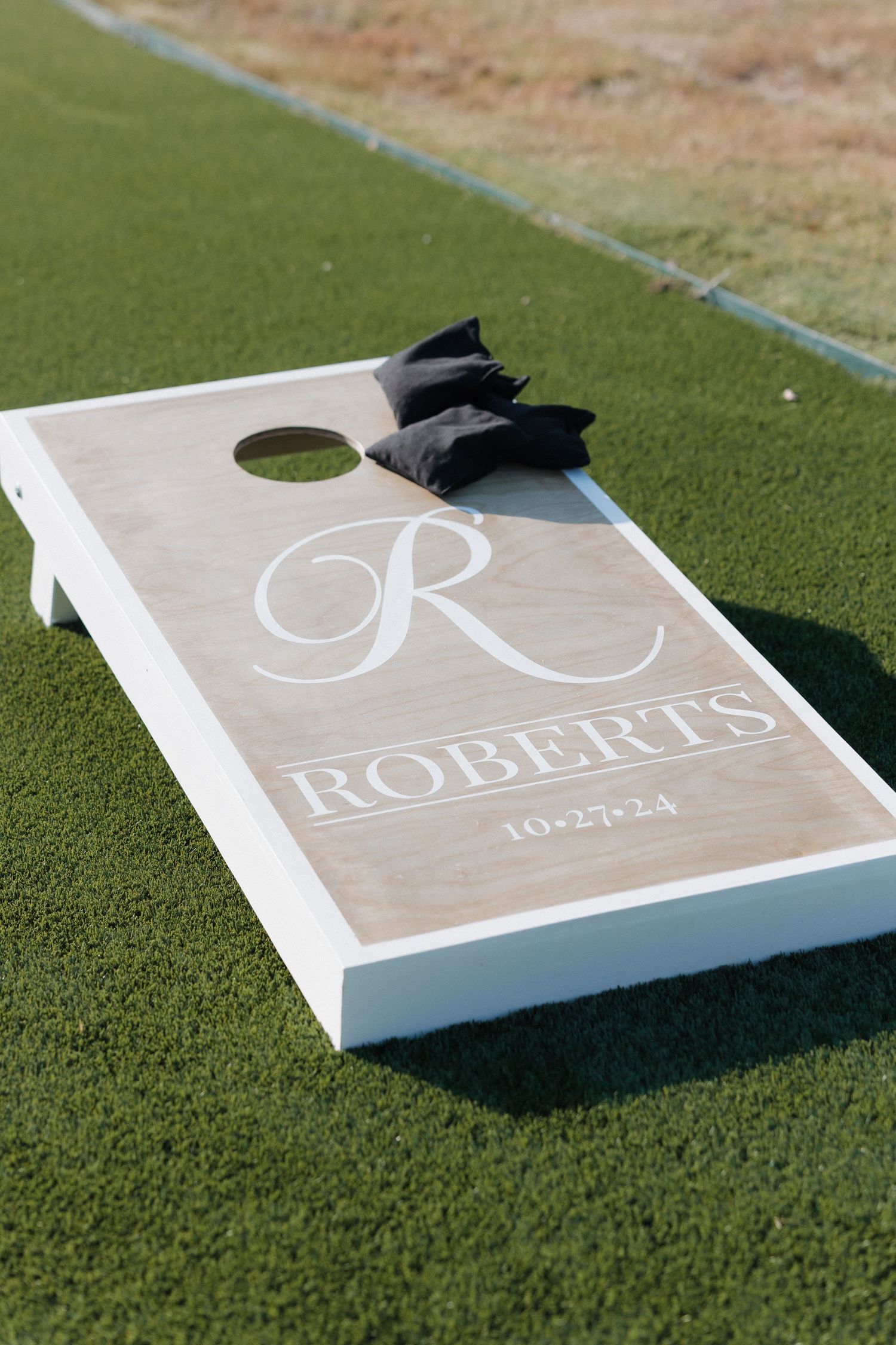 Custom white cornhole board with monogram Roberts design displayed on green grass in multiple angles.