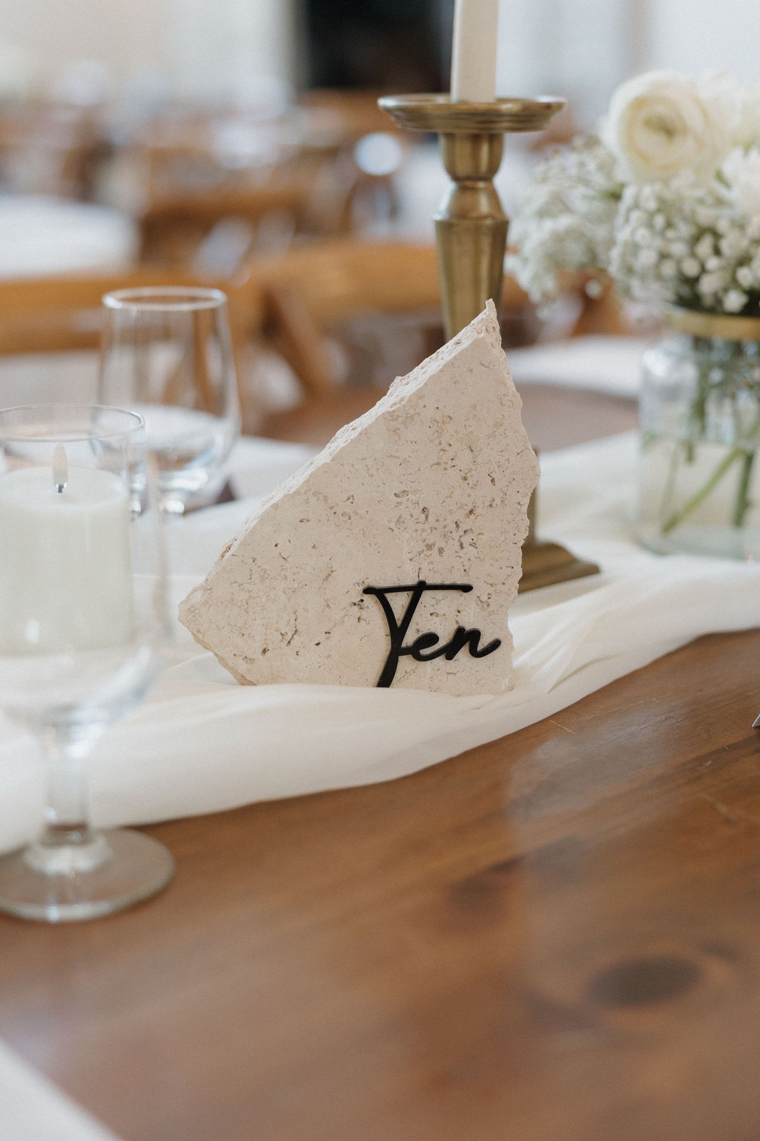 A series of white ceramic name card holders arranged in a line on a wooden table at a formal dining setting.