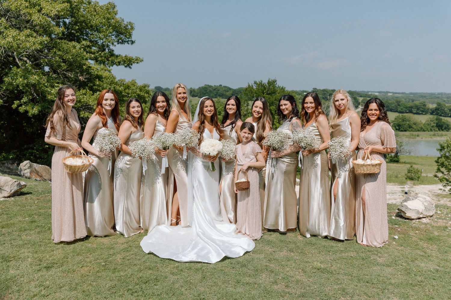 A panoramic collage of outdoor wedding party photos in neutral beige and white attire against a scenic countryside backdrop.