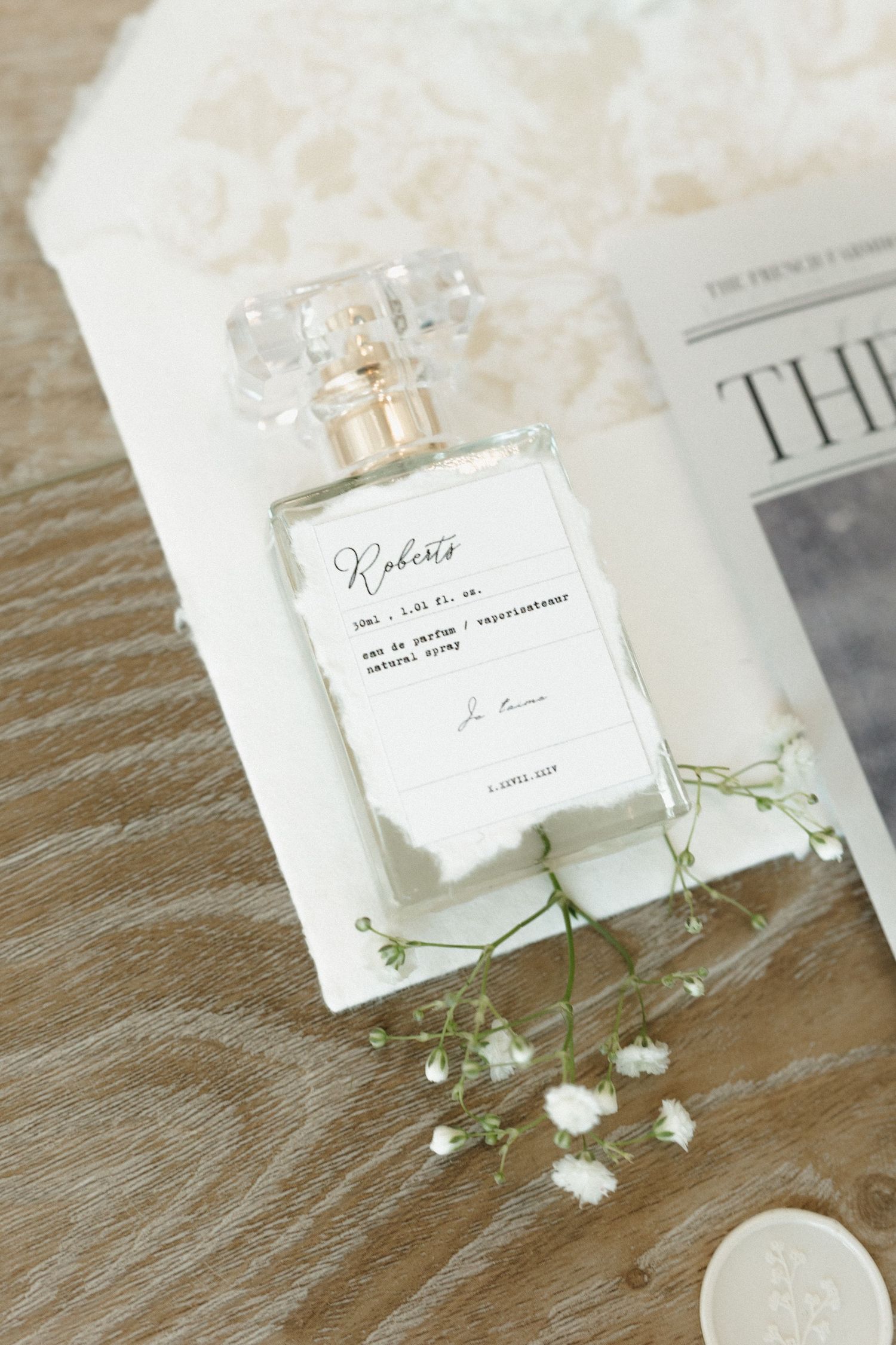 Wedding invitation cards with delicate white flowers and twine arranged on a rustic wooden surface.