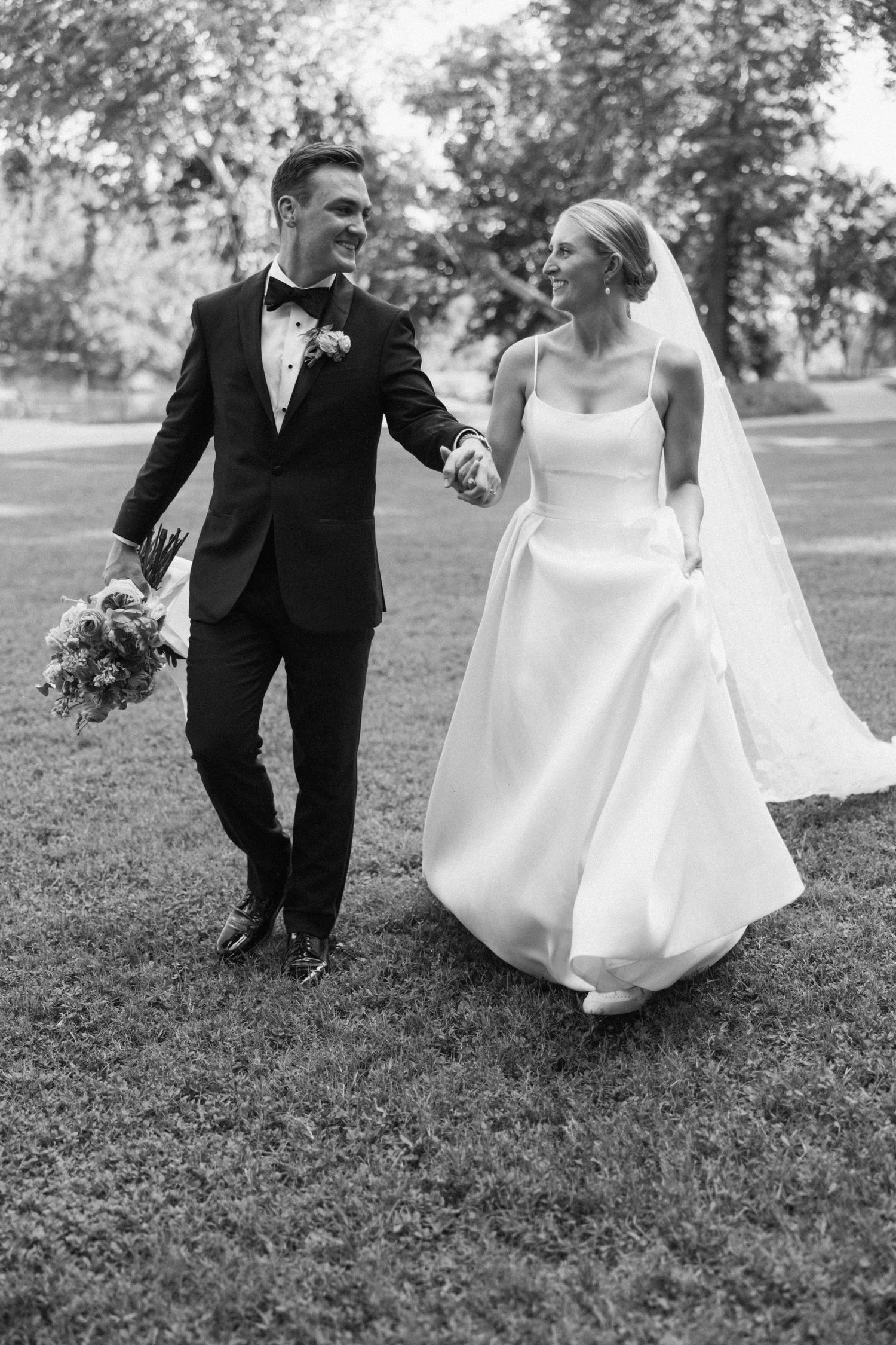 A series of black and white wedding photos showing a couple playfully sitting together on grassy ground.