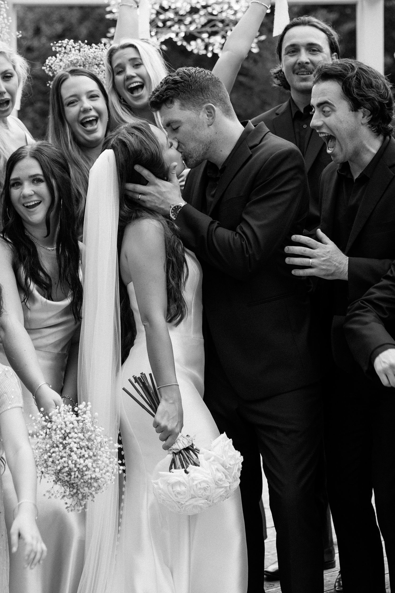 Black and white photo sequence showing joyful wedding party members laughing together during outdoor celebration.