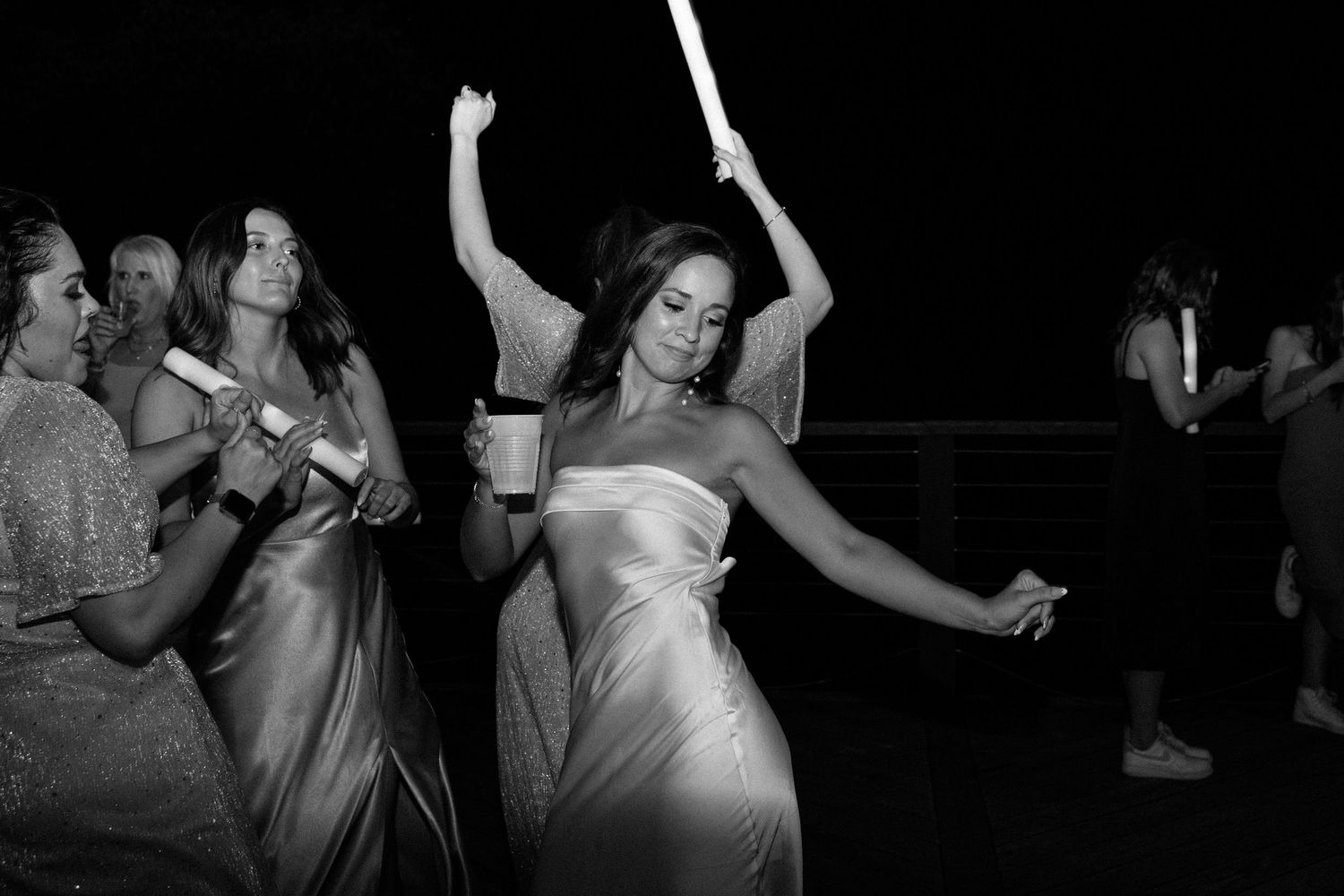 A group of people dancing together in a dark room at what appears to be a nightclub or party.