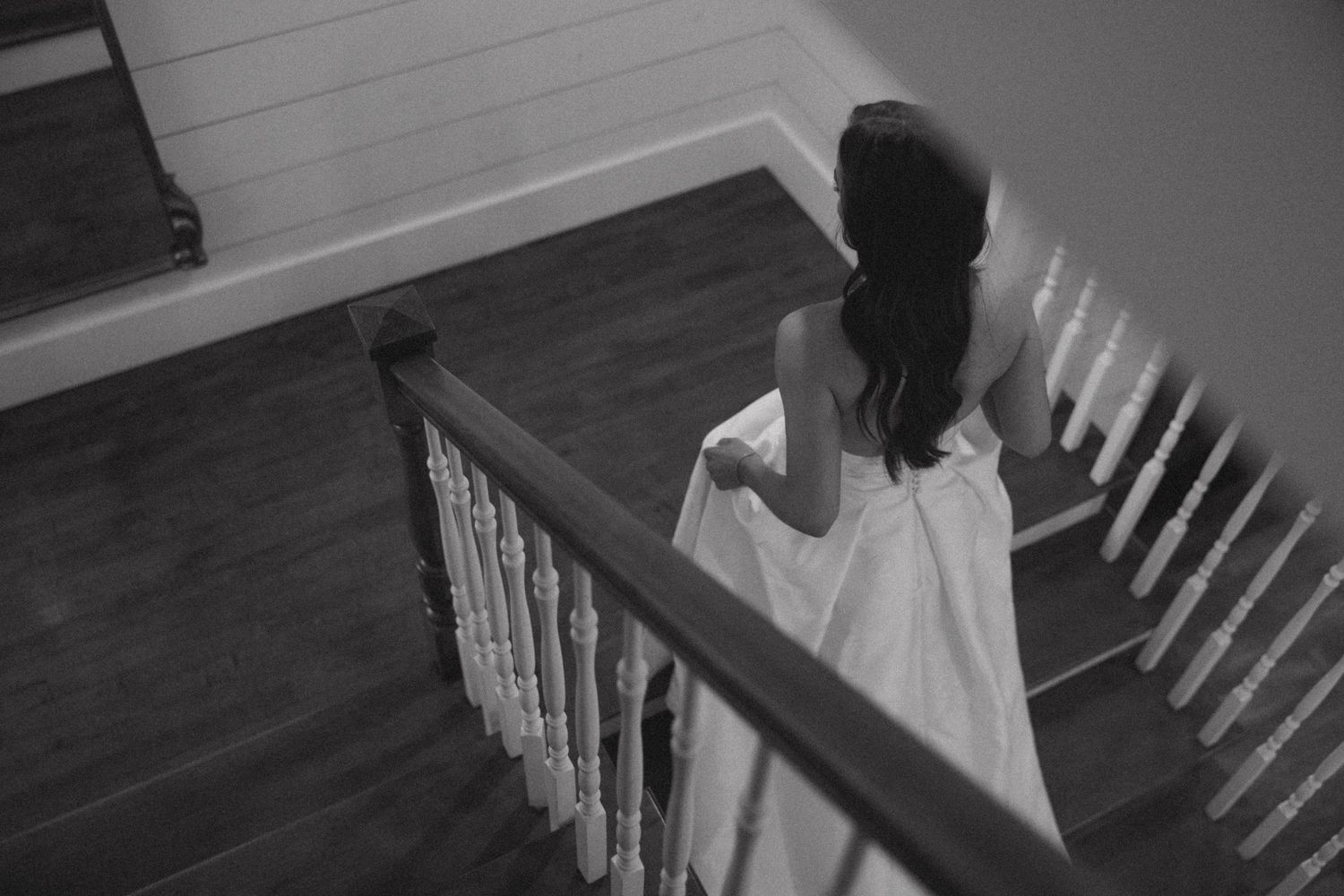 A sequence of black and white photos showing someone walking down a staircase with white spindles and railings.