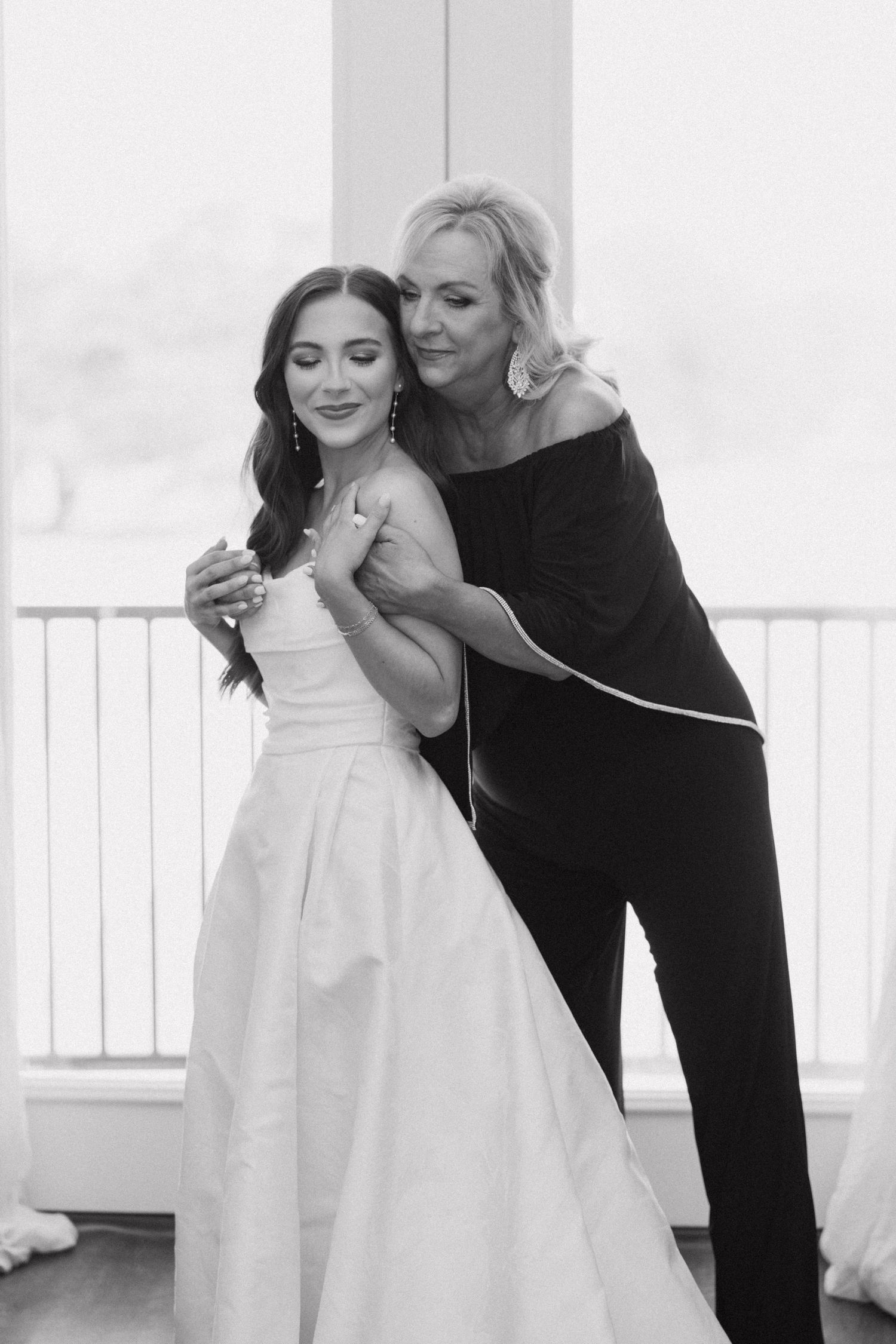 A tender dance moment captured in black and white as two people embrace on a light-filled balcony.
