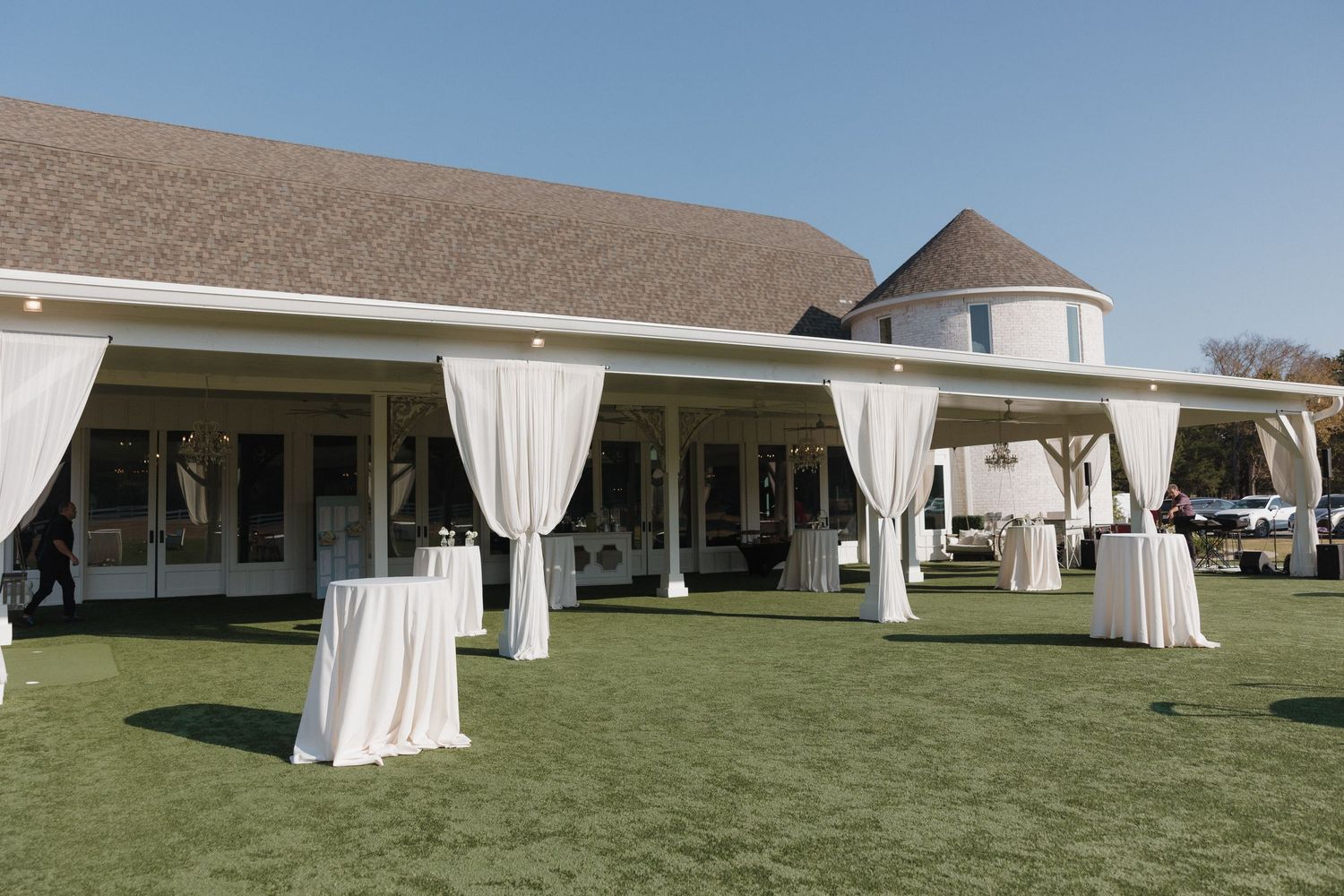White outdoor wedding tent pavilions with flowing curtains set up on a grassy lawn for an elegant event.