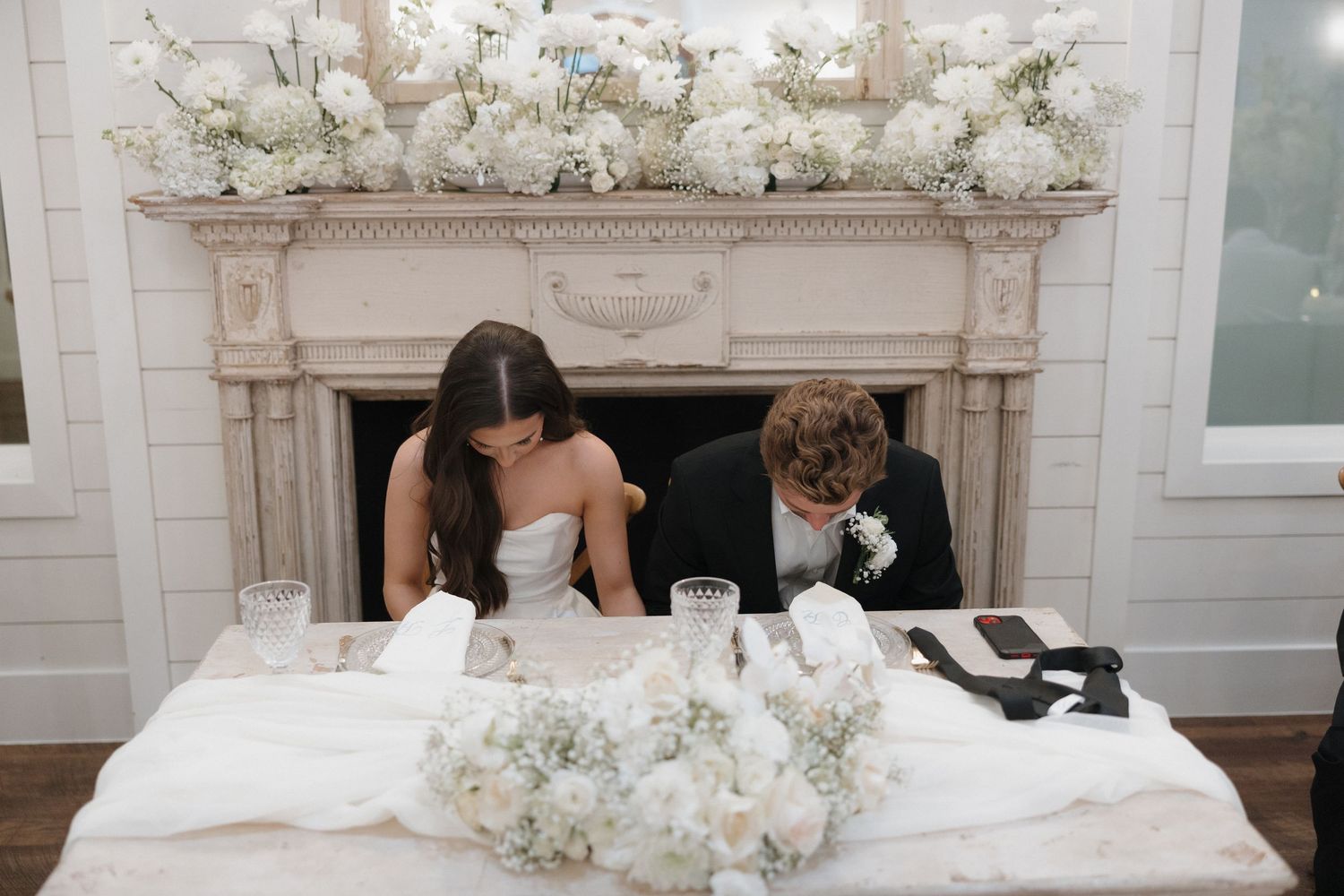 White and blush floral arrangements decorate an elegant indoor wedding ceremony space with ornate architectural details.