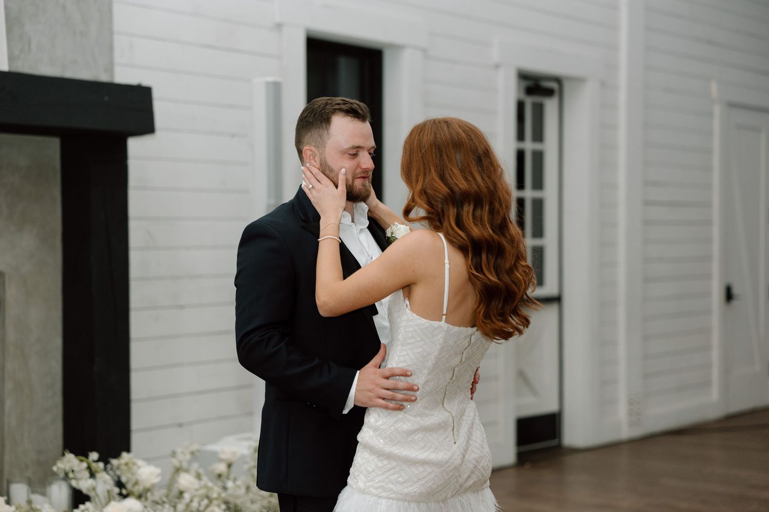 A bride and groom share a romantic dance in front of a white building during their wedding celebration.
